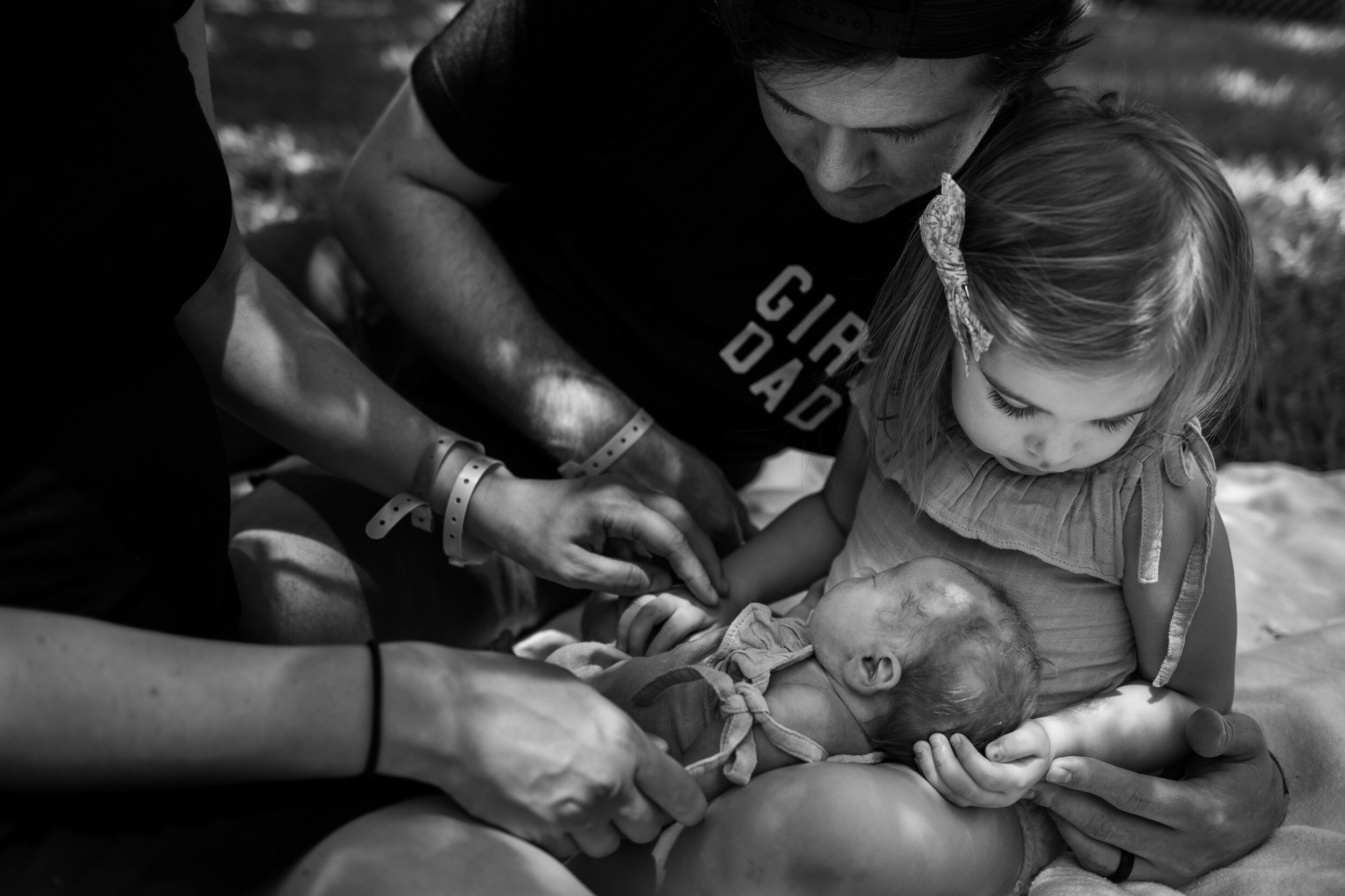 little girl inspecting every detail of her newborn baby sister