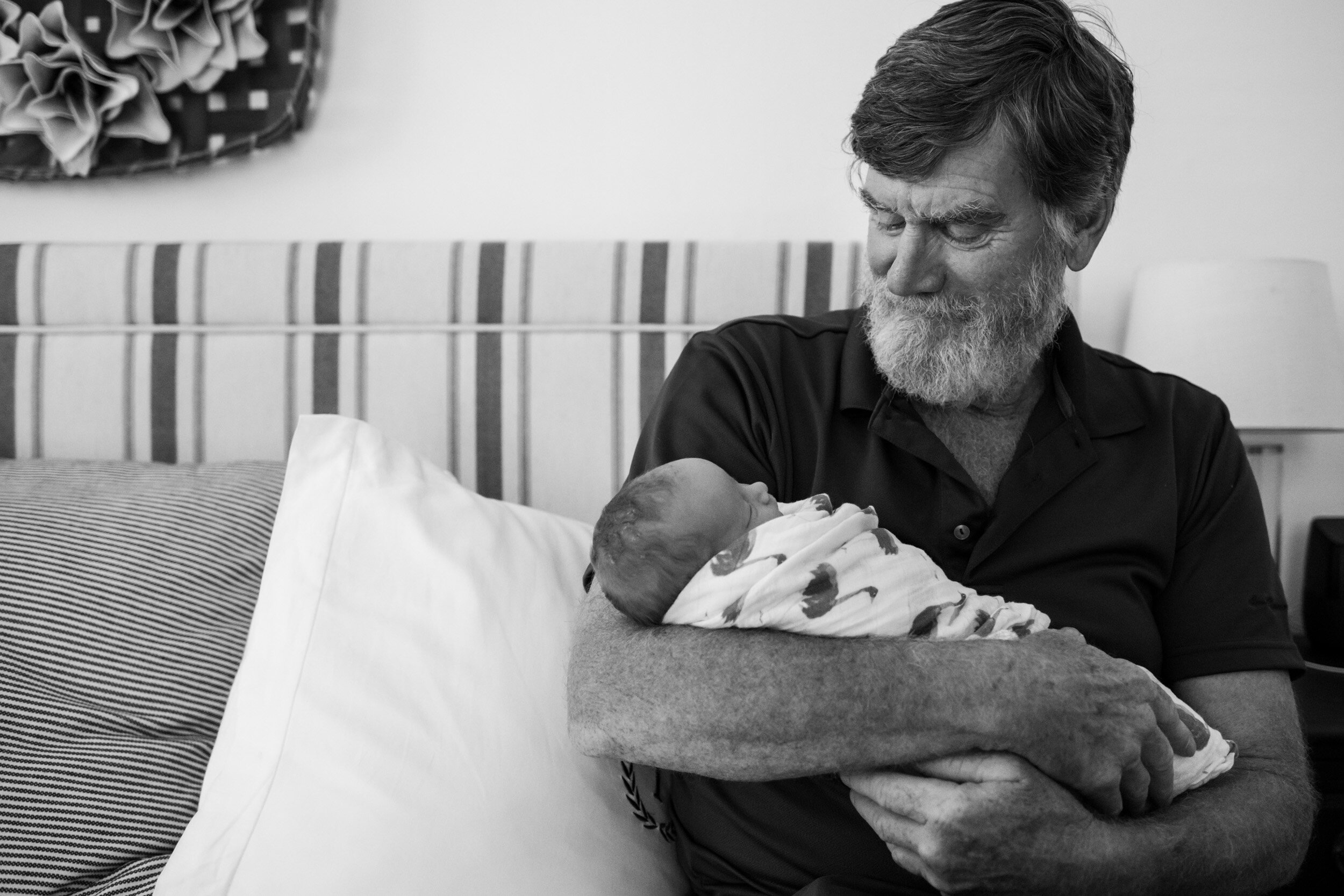 grandfather holding his newborn granddaughter and smiling