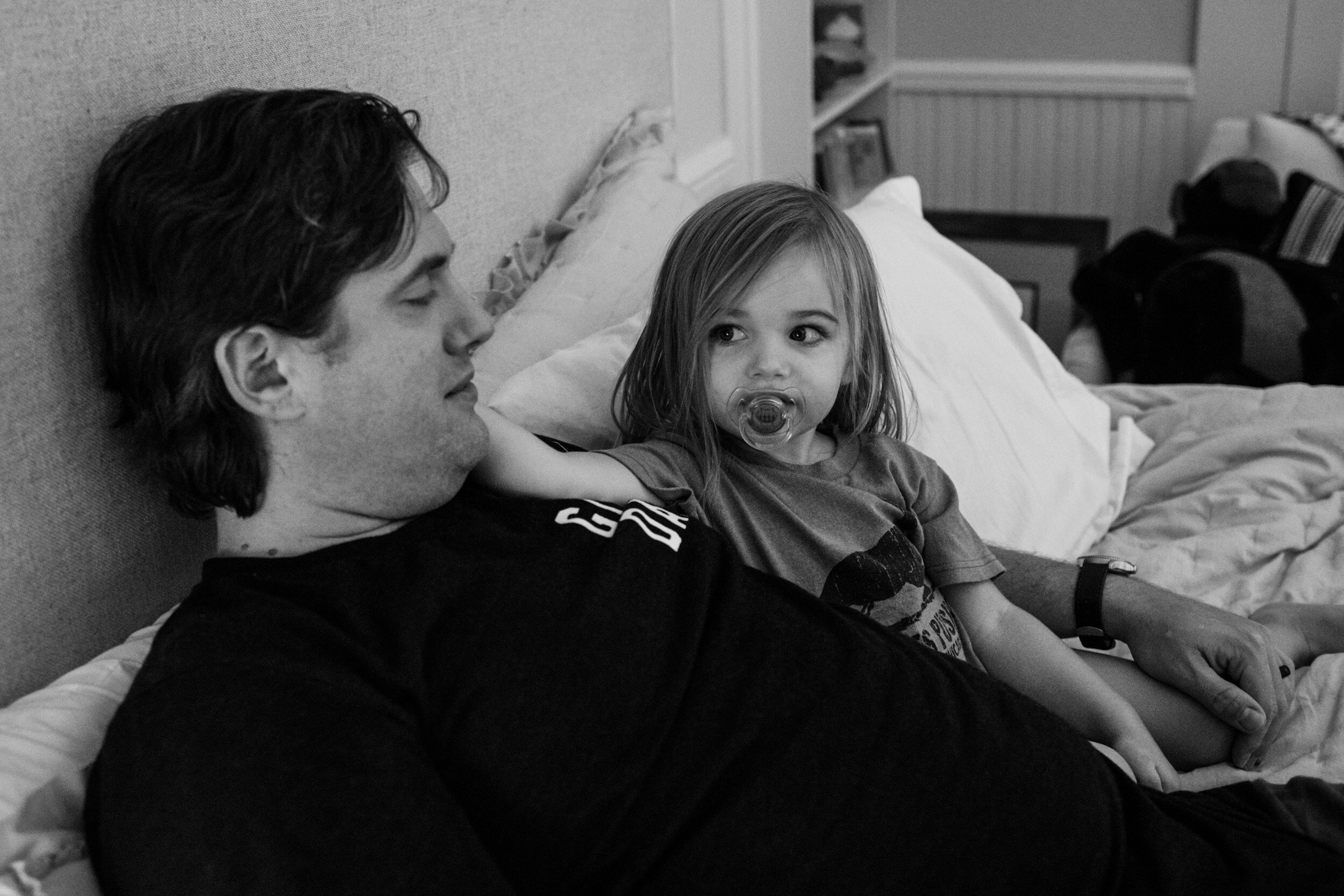 little girl looking at her dad while he gets her settled into bed