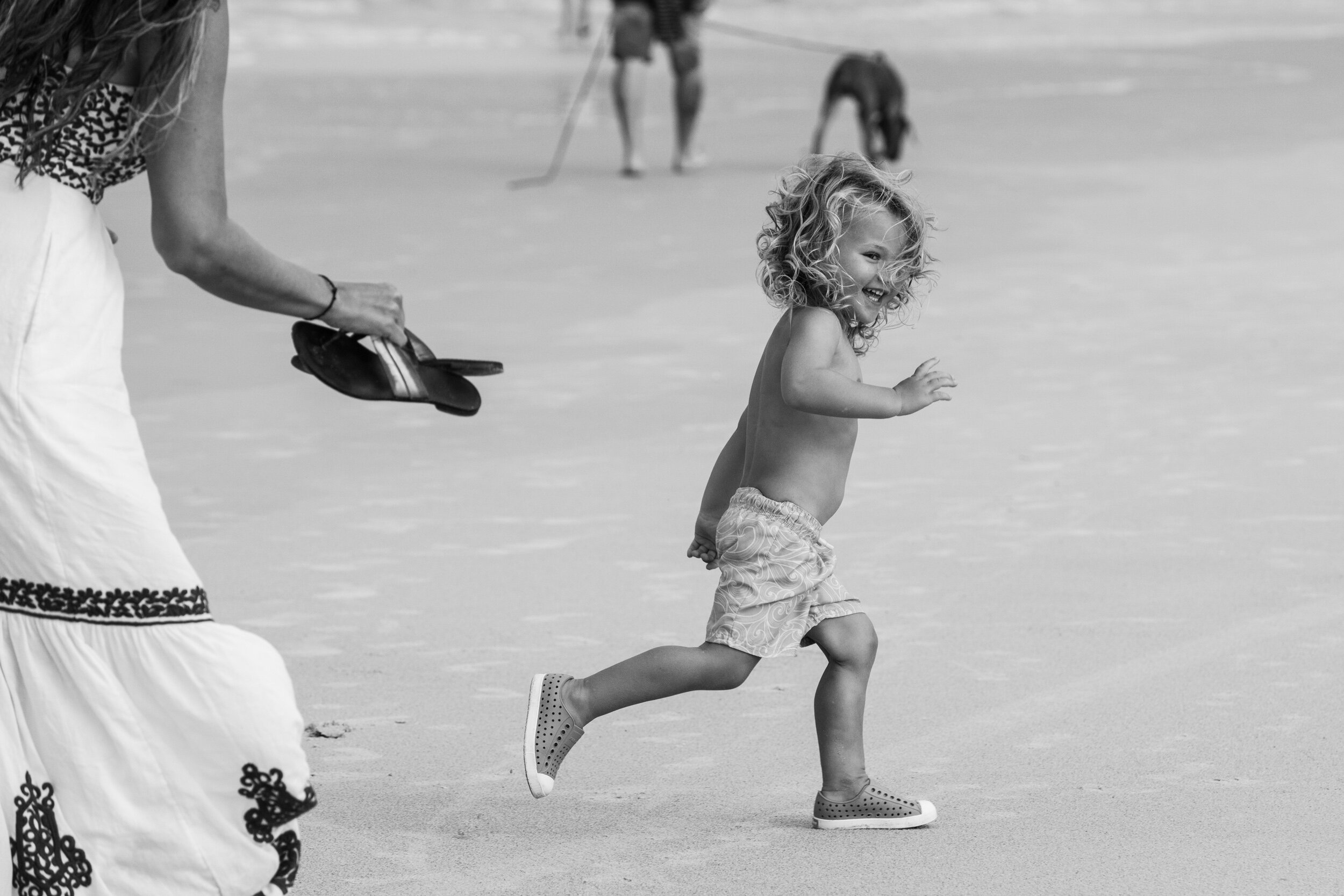 little boy running away from mom at the beach