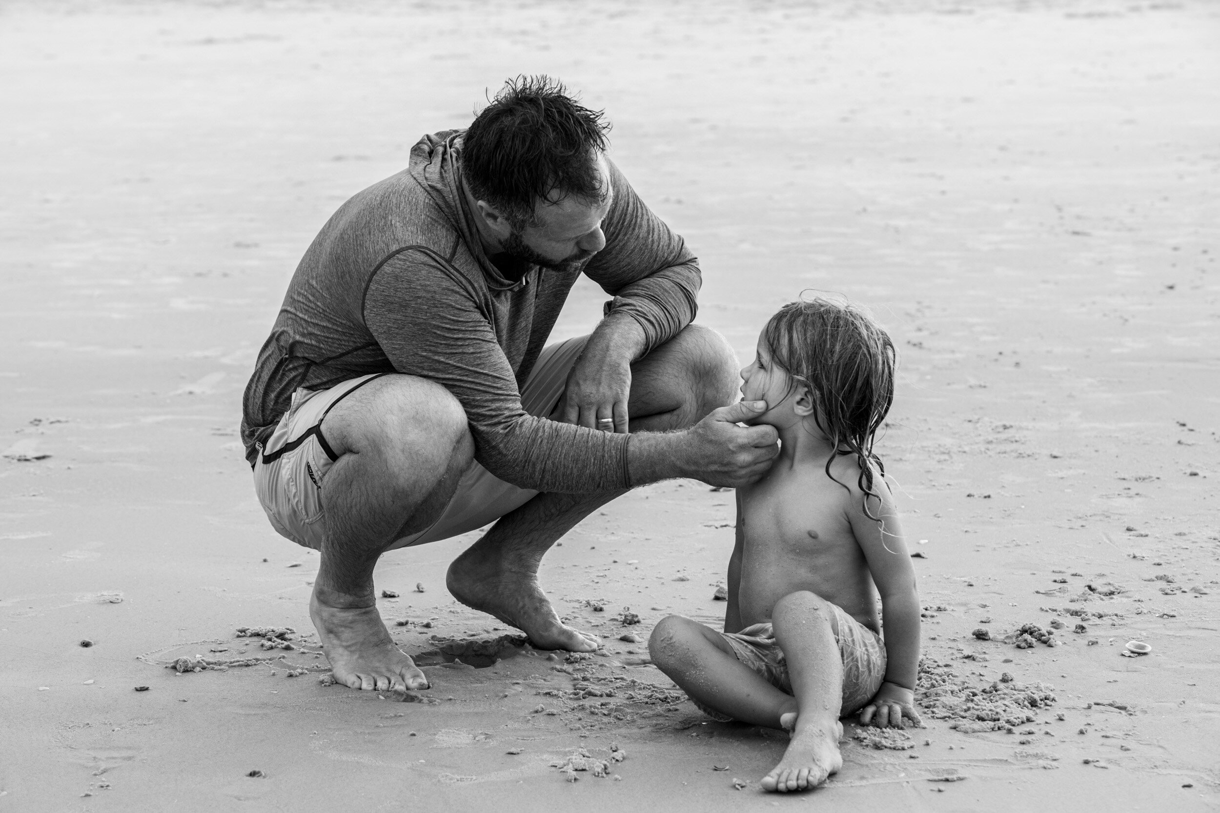 dad comforting son at the beach