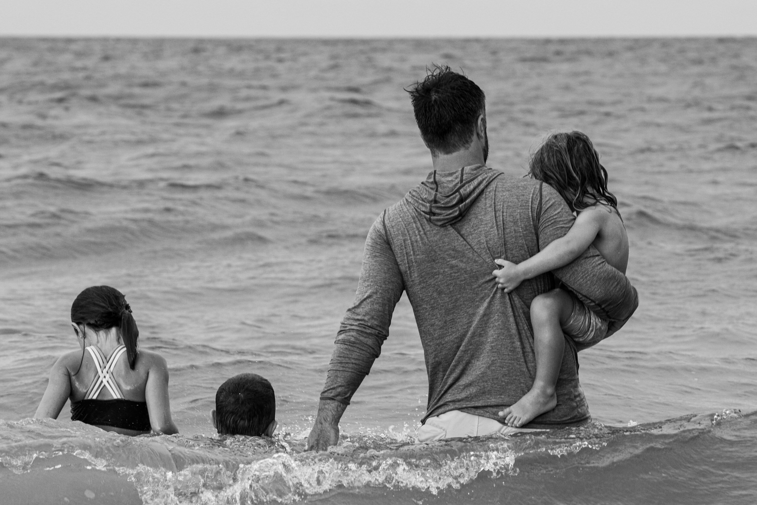 little boy holding onto his dad as they enter the waves at anastasia island