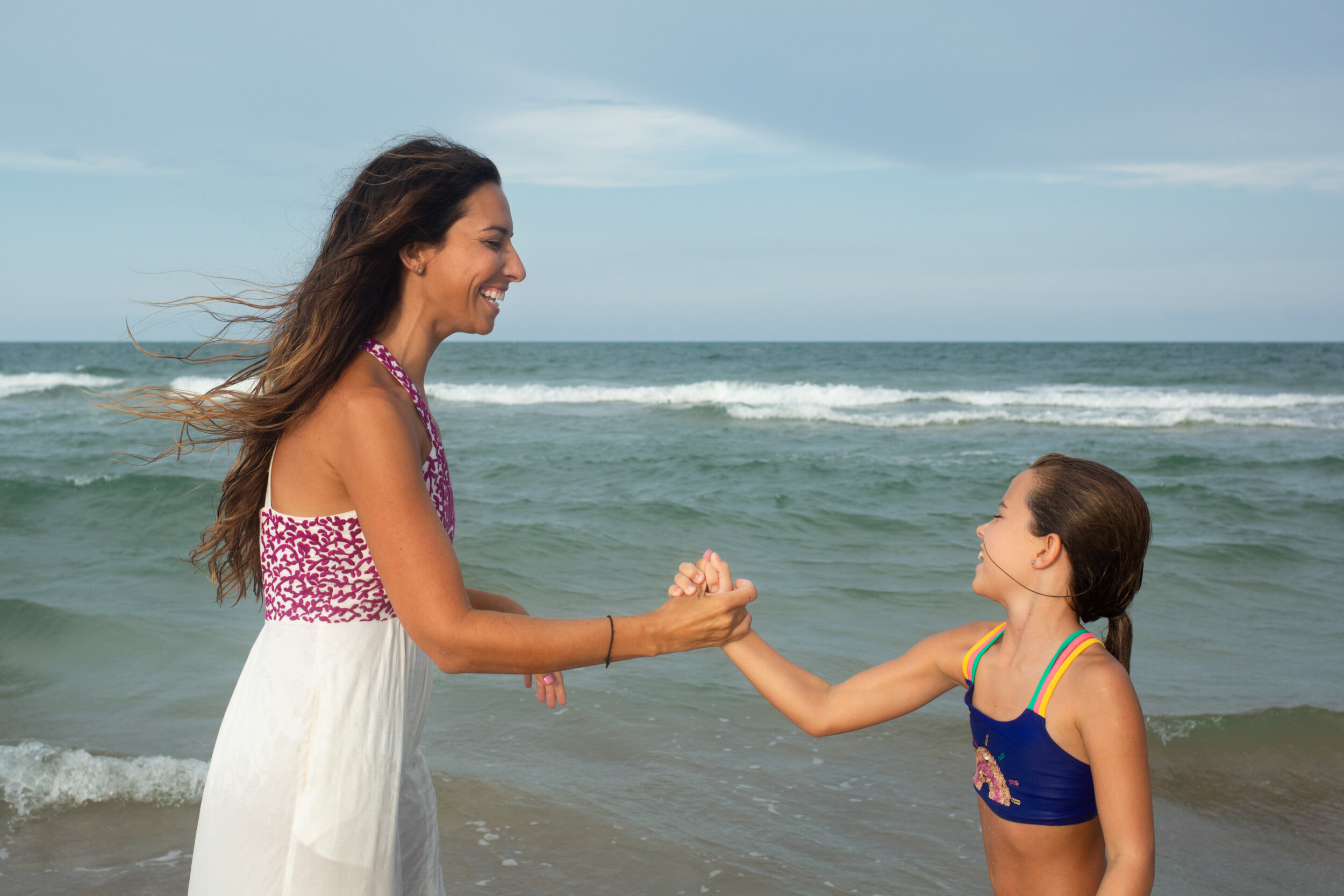 little girl and mom doing a handshake at the beach