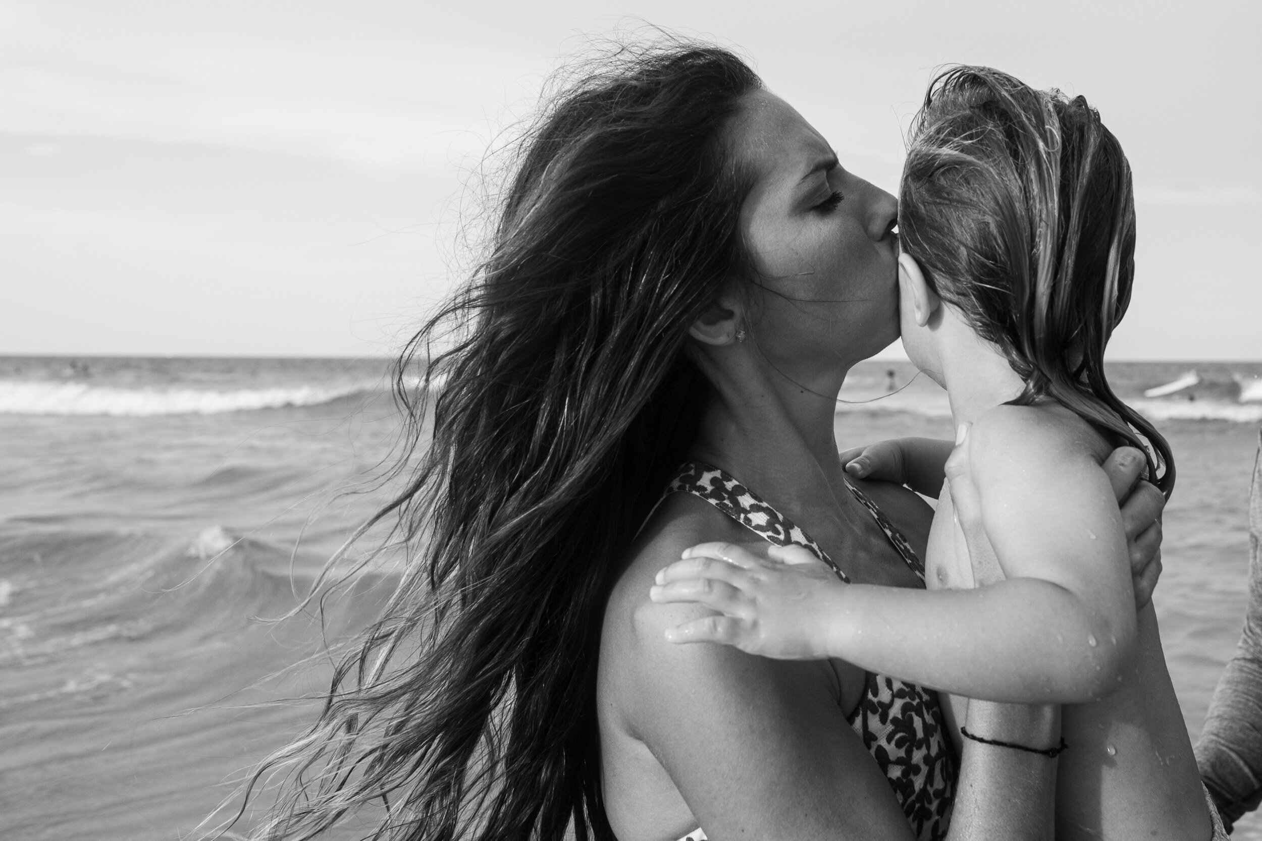 mom kissing her little boy at the beach on anastasia island