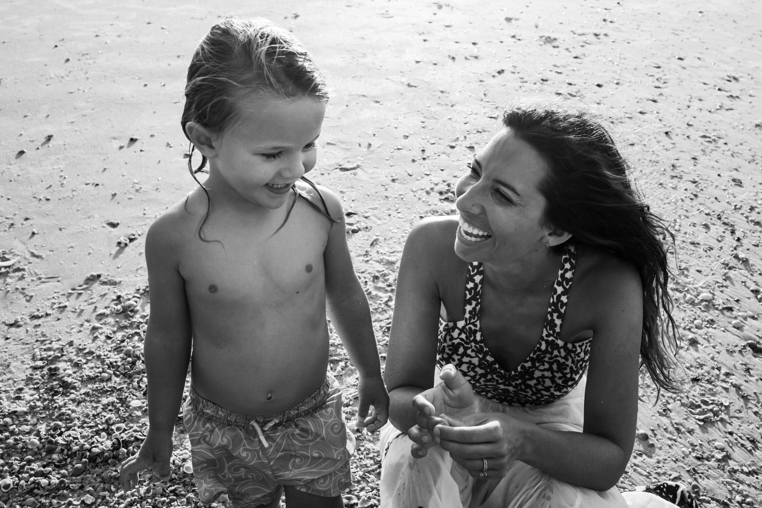 mom smiling at her son at the beach
