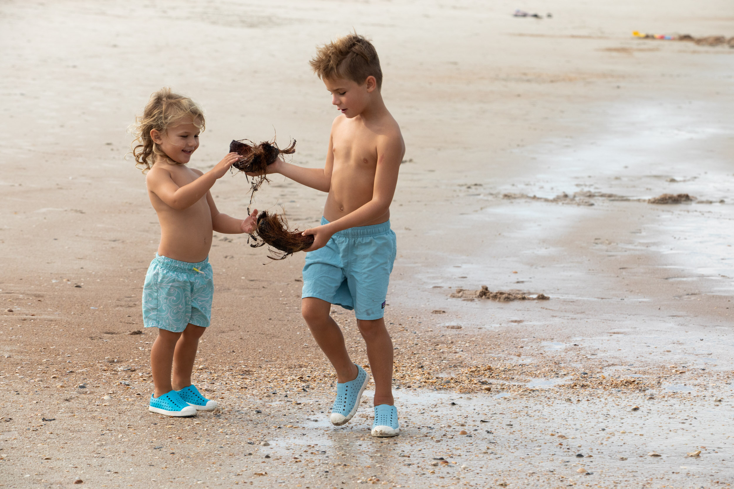 little boys playing with coconut shells at the beach
