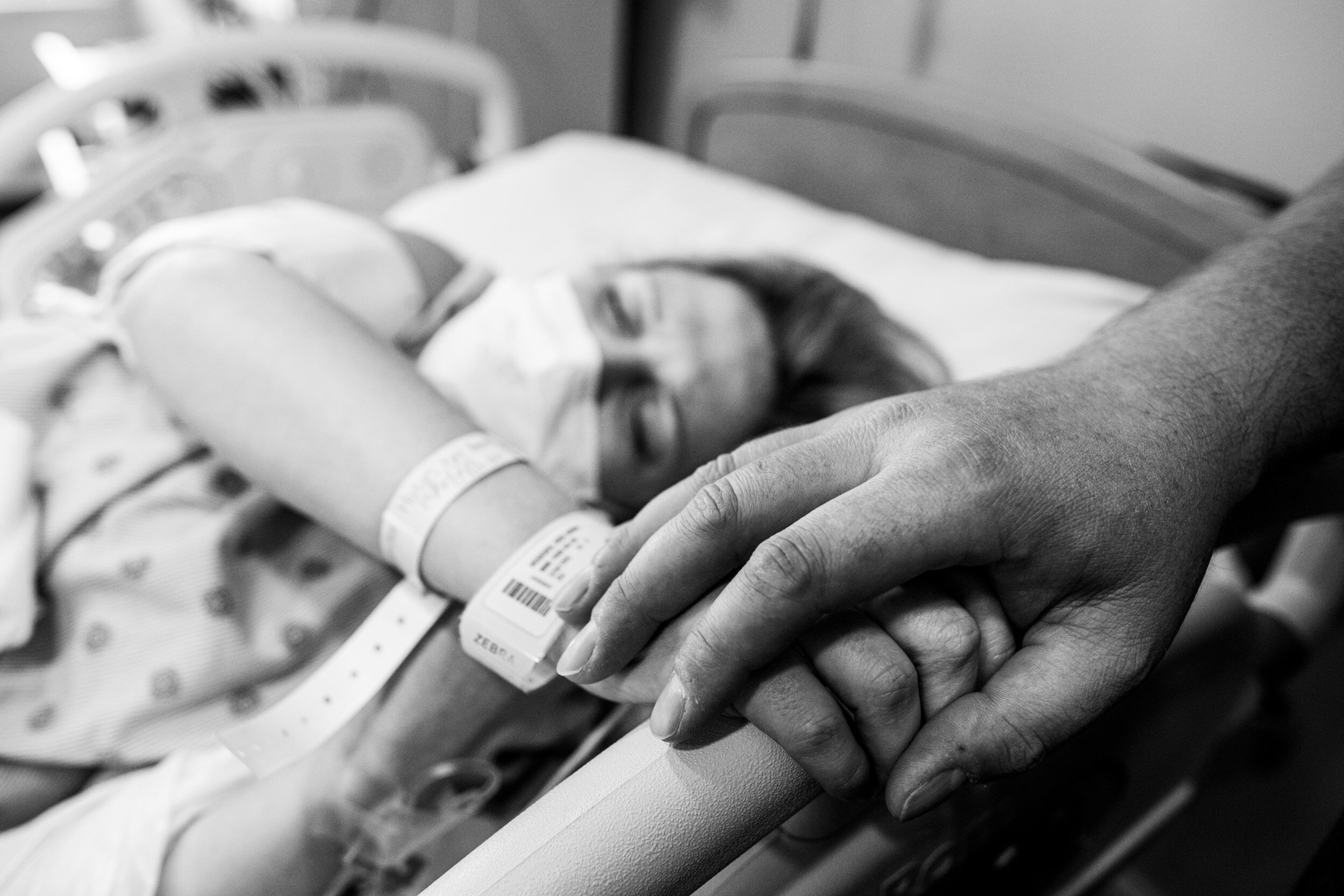 husband's hand on his wife's hand while she's in labor
