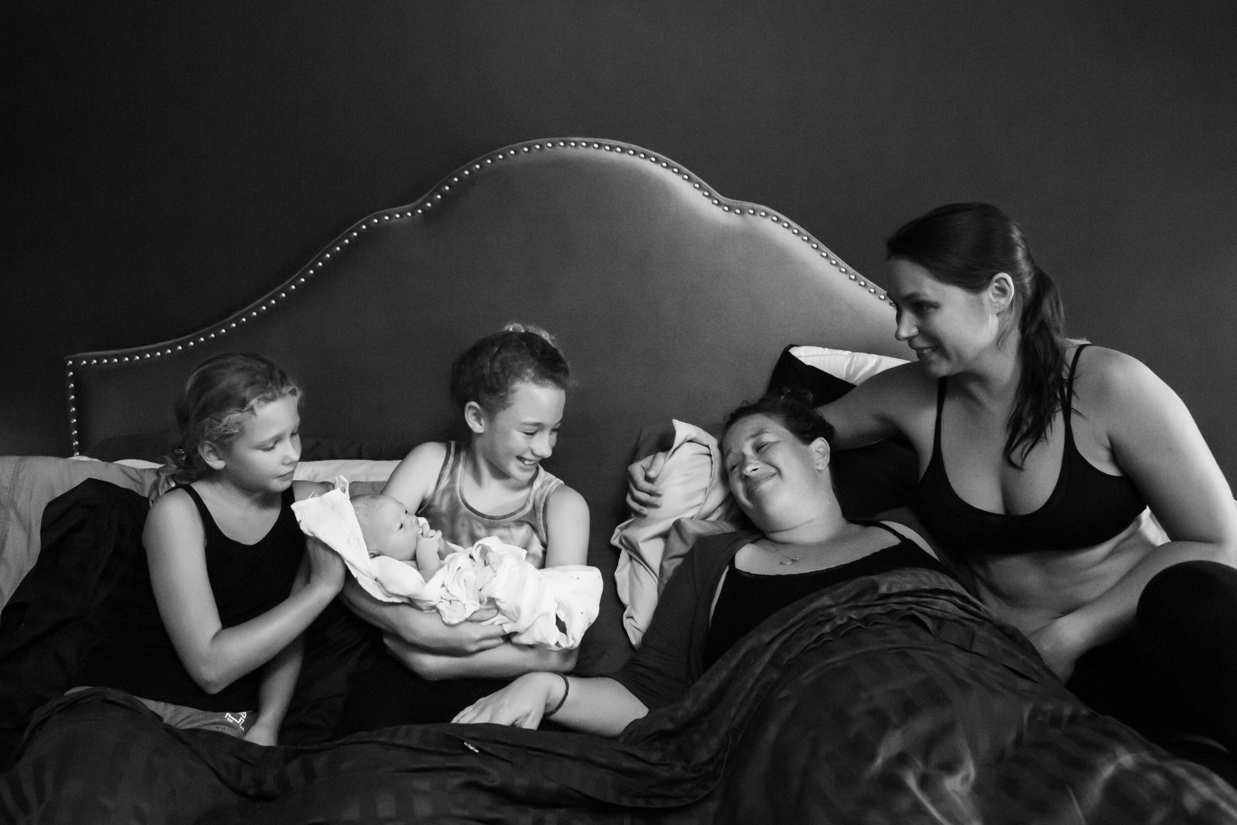 new family smiling as they hold new baby born at home