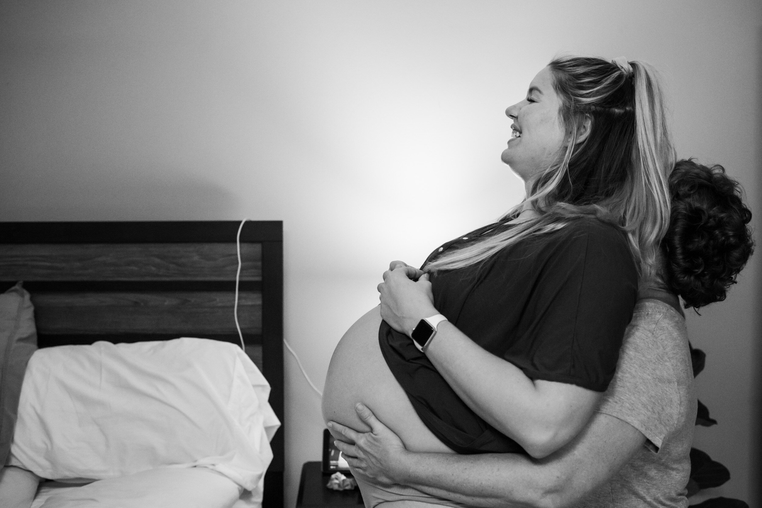 doula lifting up mom's belly from behind during labor