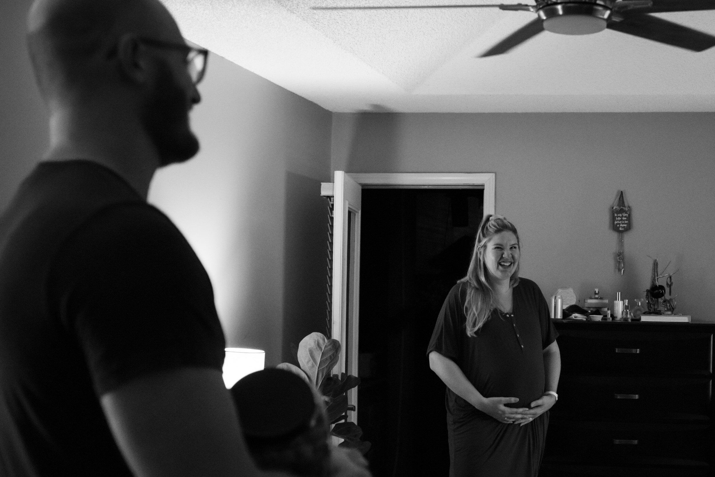 pregnant mom smiling at husband while holding her belly