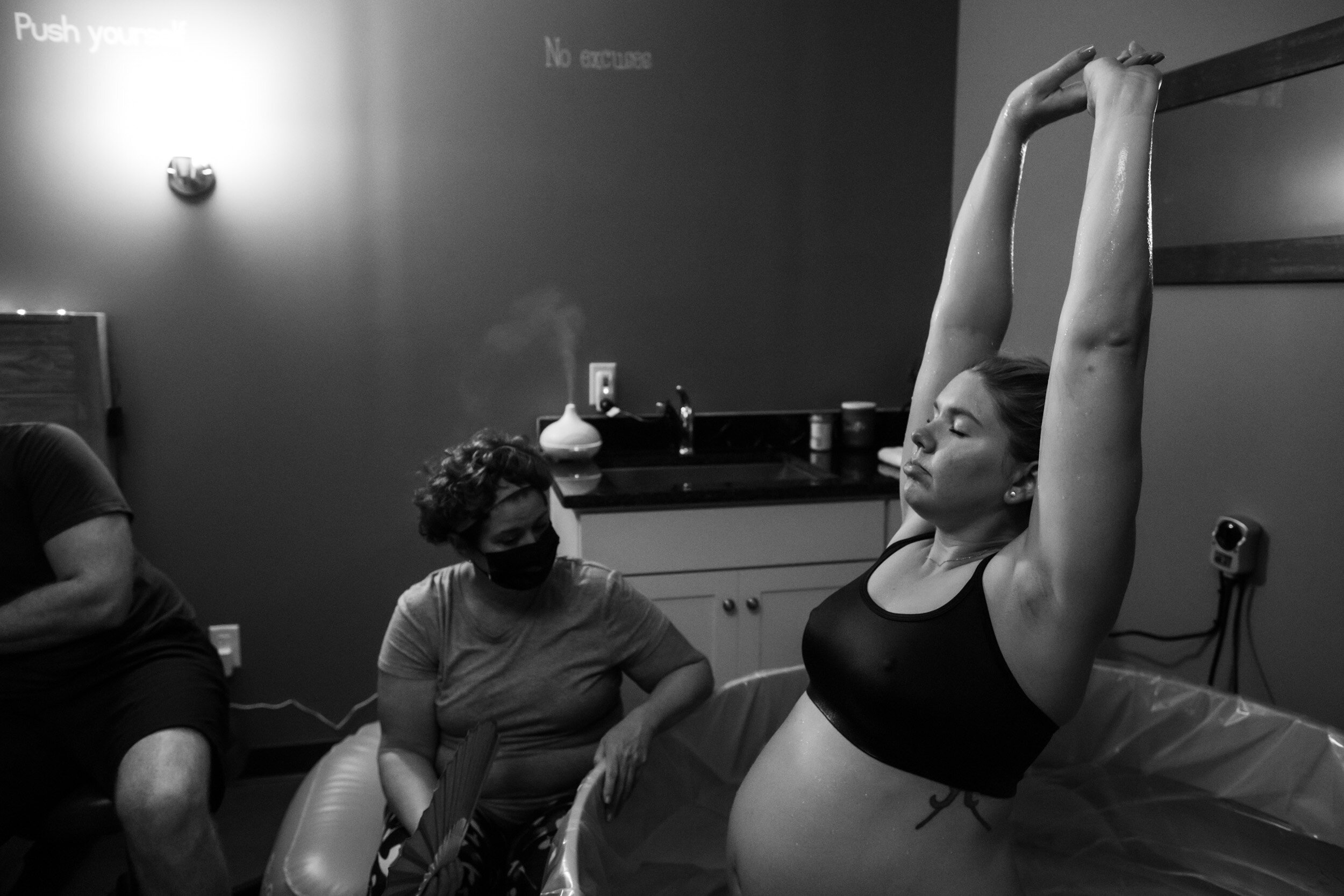 pregnant mom stretching up while laboring in birth pool