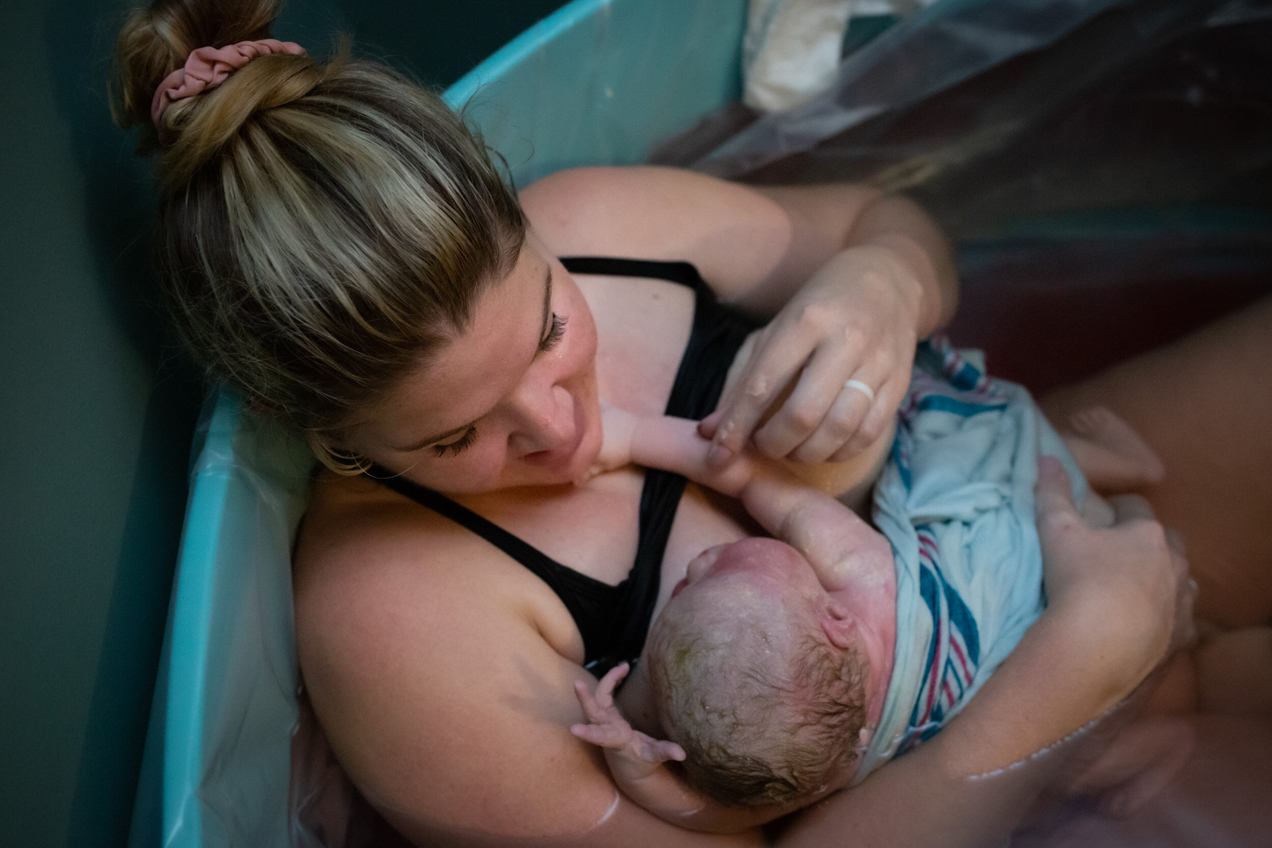 birth mom looking at her baby girl while resting in the birth tub