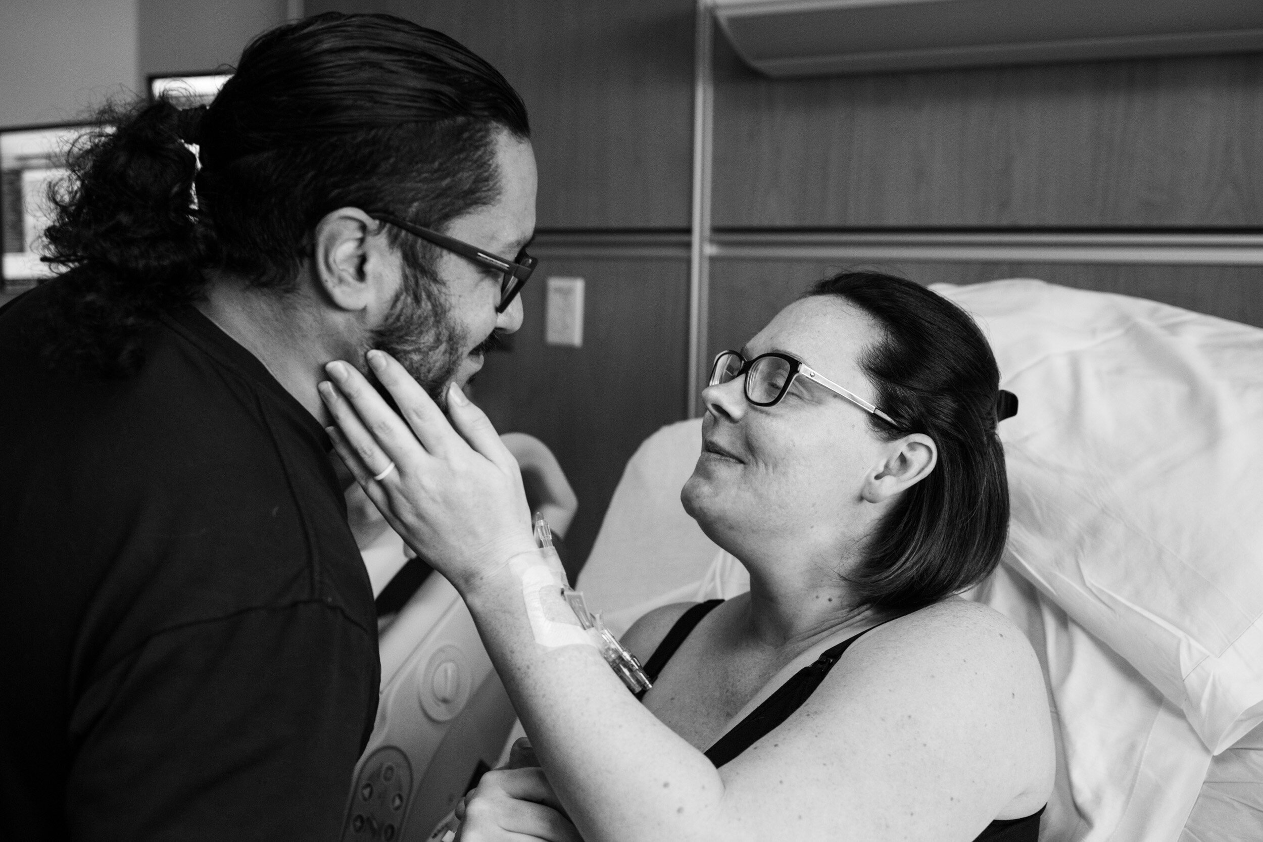 wife holding husband's face and smiling just after their baby was born