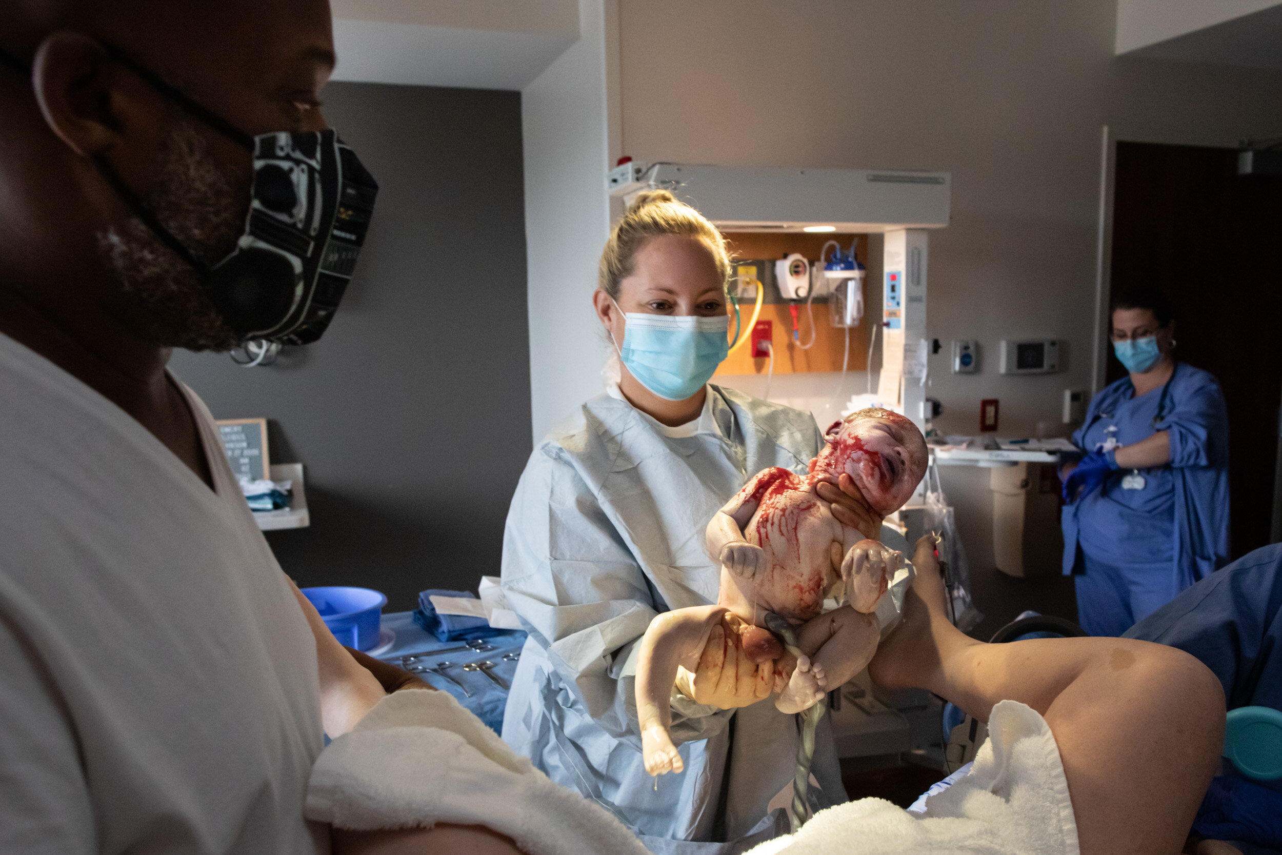 midwife holding up newborn baby boy just after birth