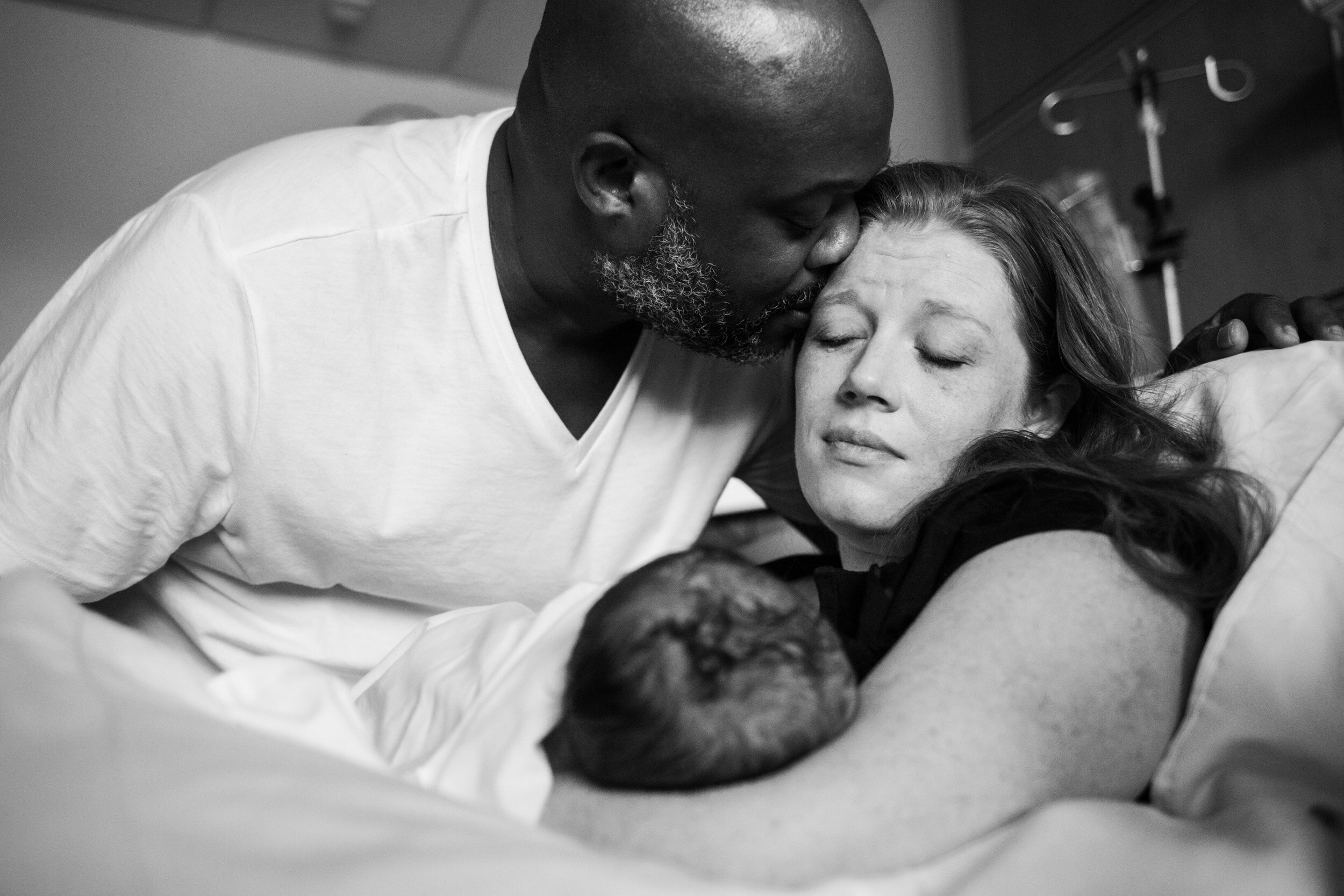 husband kissing his wife just after the birth of their first child