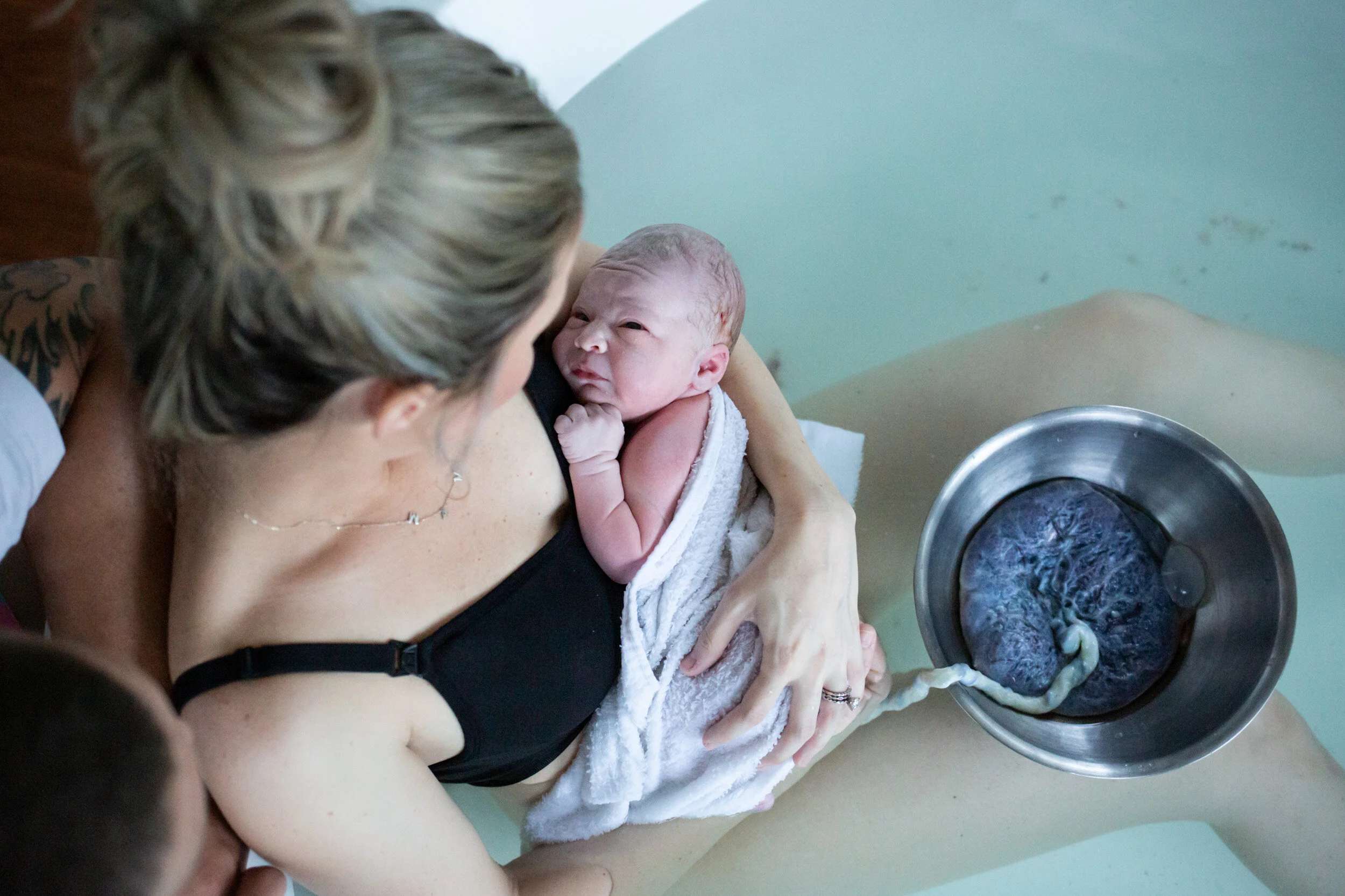 newborn baby still attached to placenta, looking at her mom