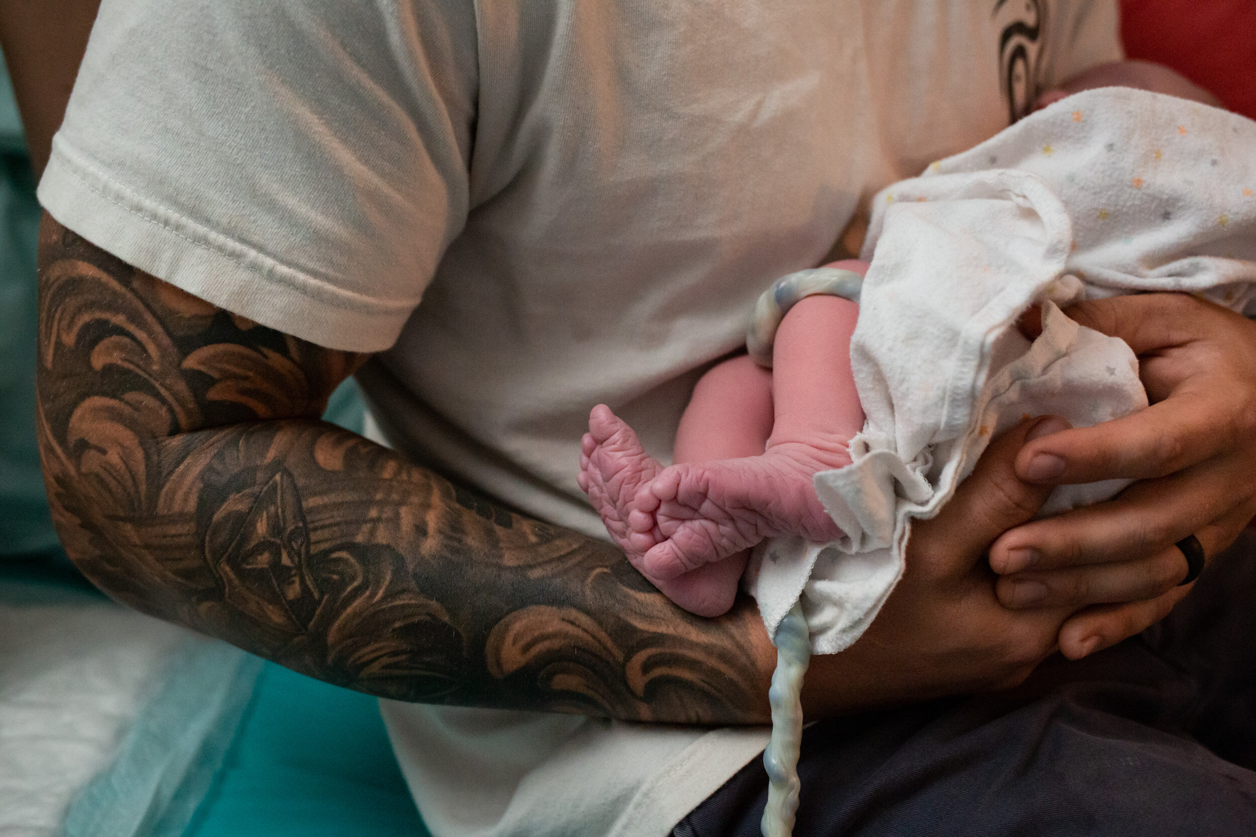 dad with tattoos holding newborn baby