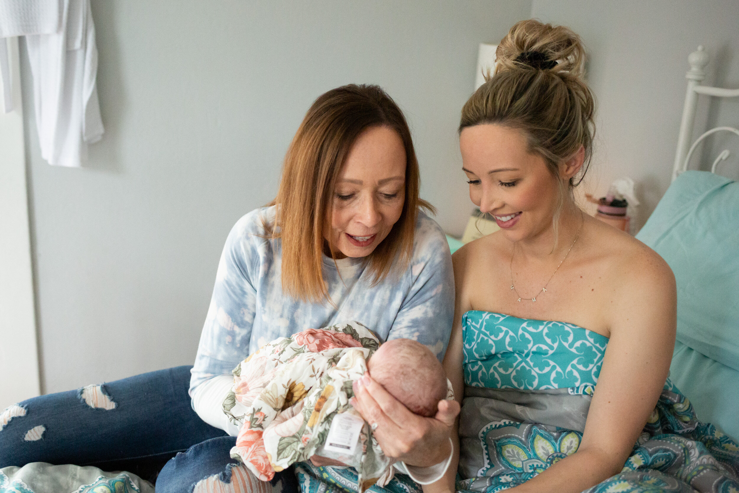 Mom and grandmother looking at newborn baby girl