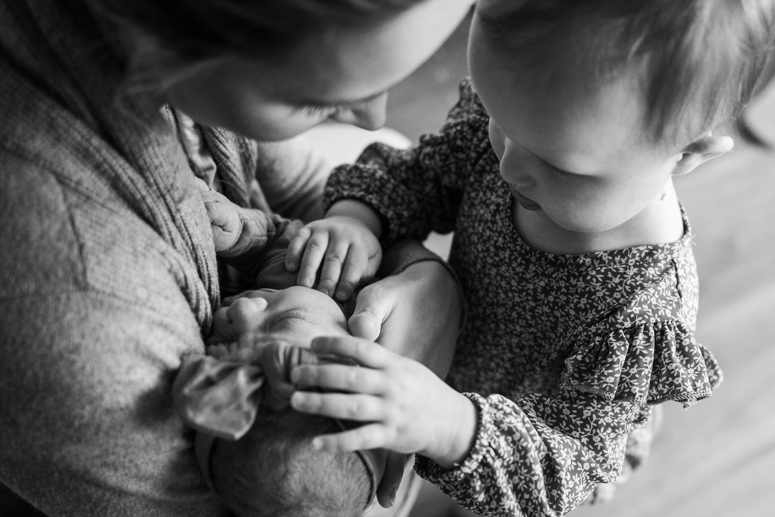 Toddler touching her newborn baby sister