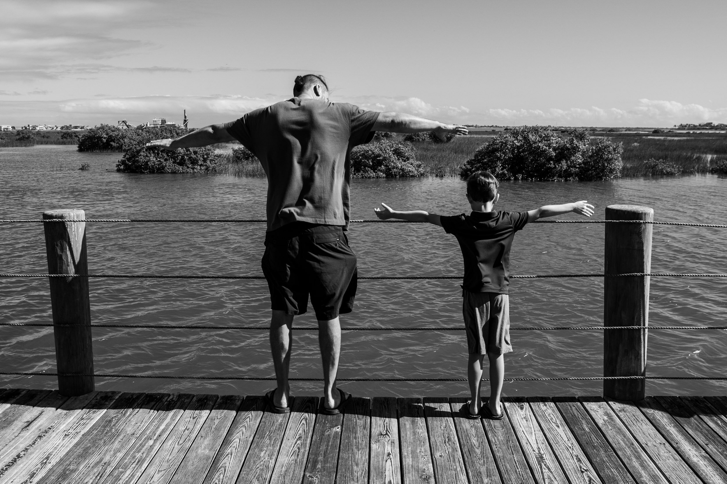 father and son looking at the river with arms out wide