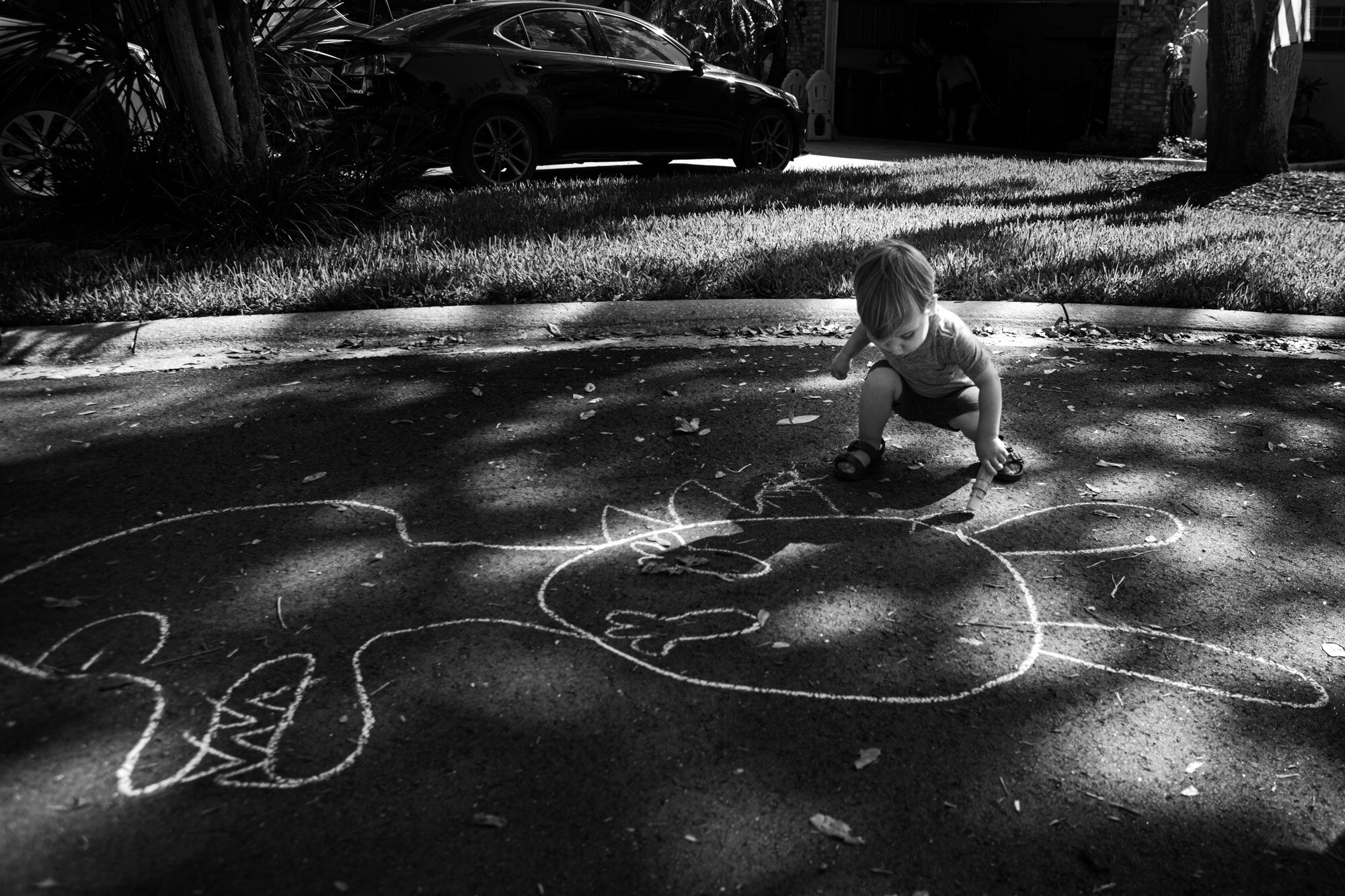 little boy drawing with sidewalk chalk