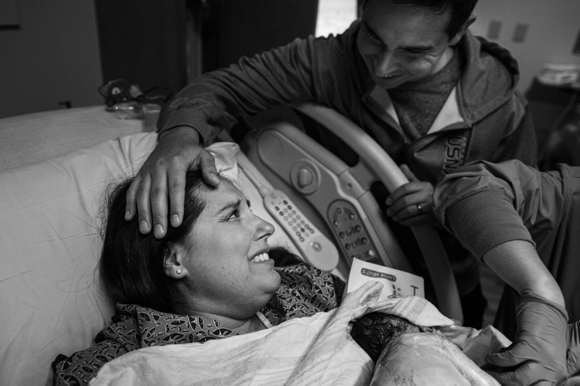 new parents smiling at each other just after the birth of their baby