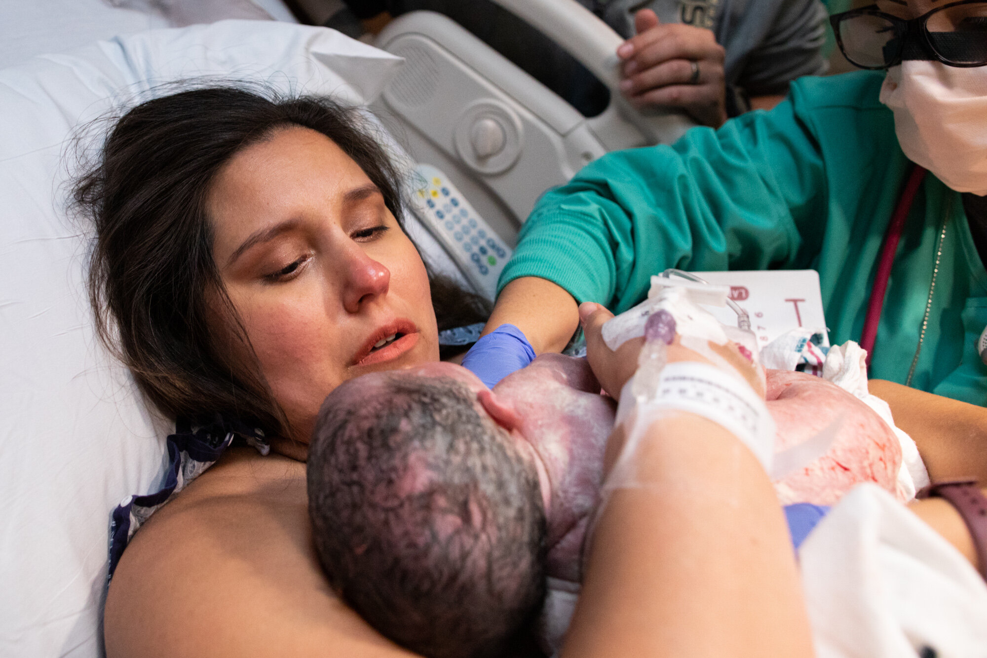 birth mom crying just after her baby was born, as she holds him in her arms