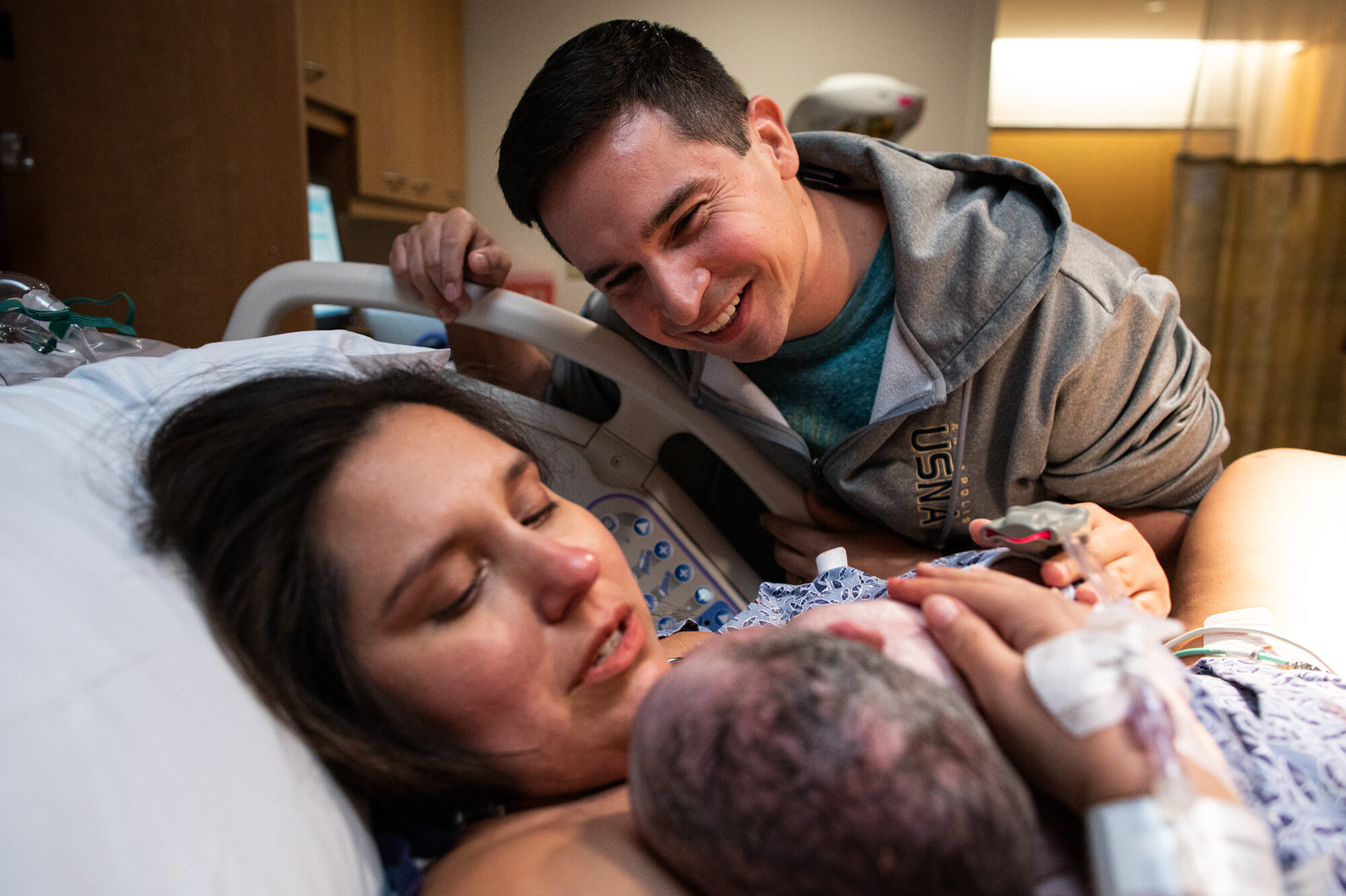 new dad smiling at his wife and newborn baby boy