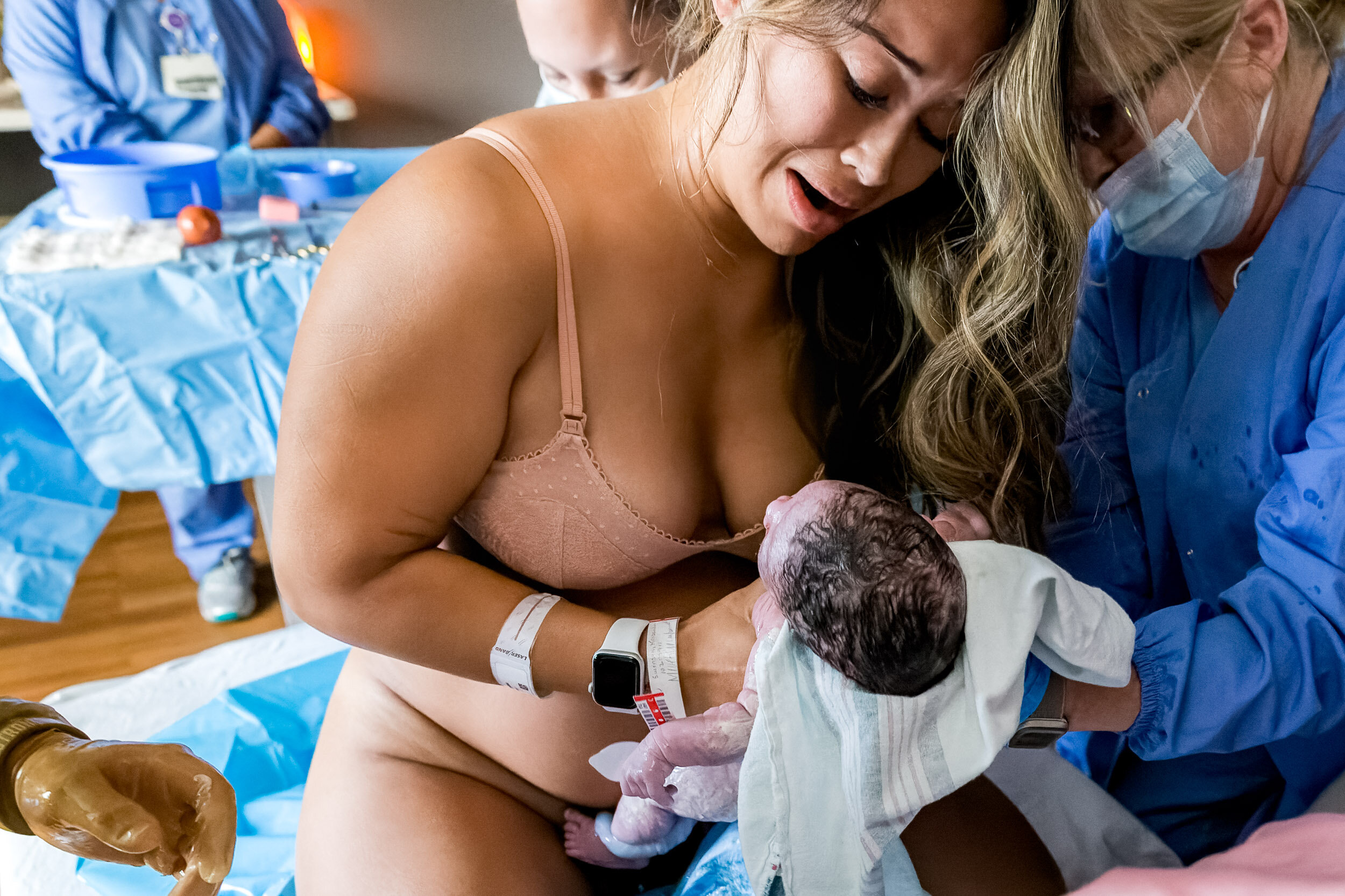 new mom picking up her newborn baby girl just after birth