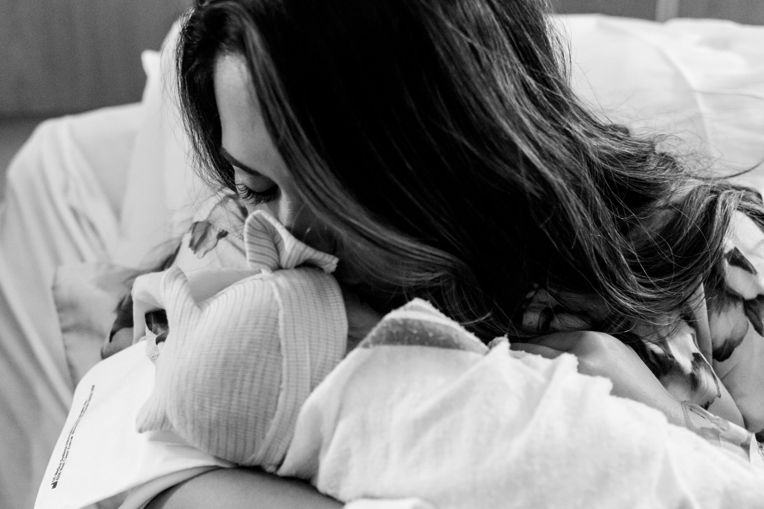 new mom kissing her baby girl just after birth