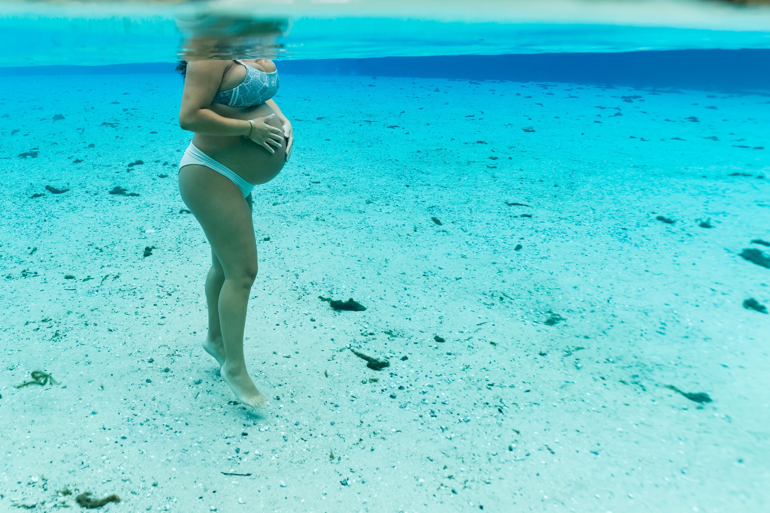 underwater photo of pregnant mom holding her belly