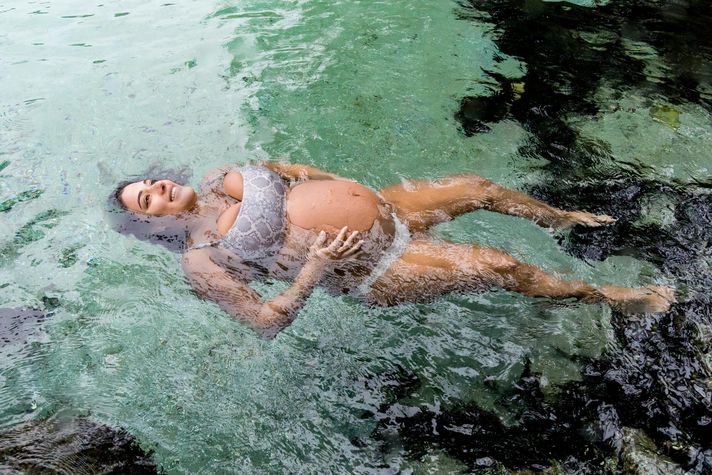 pregnant mom floating in clear spring water