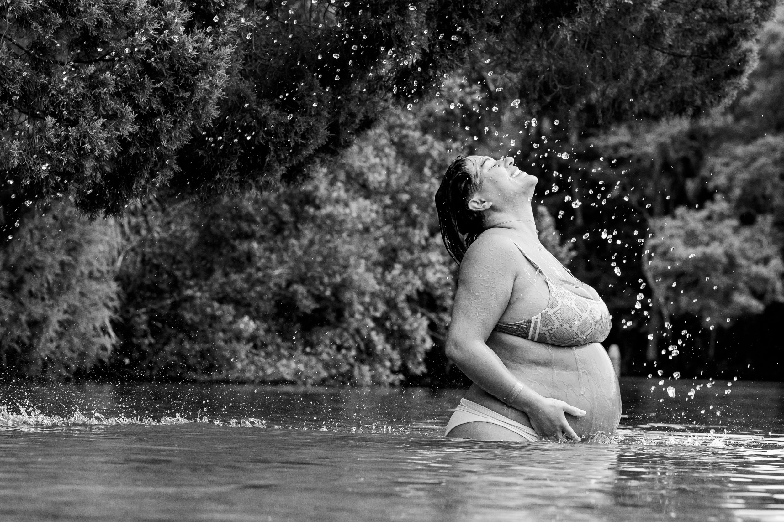 pregnant mom being splashed by droplets of water at the springs