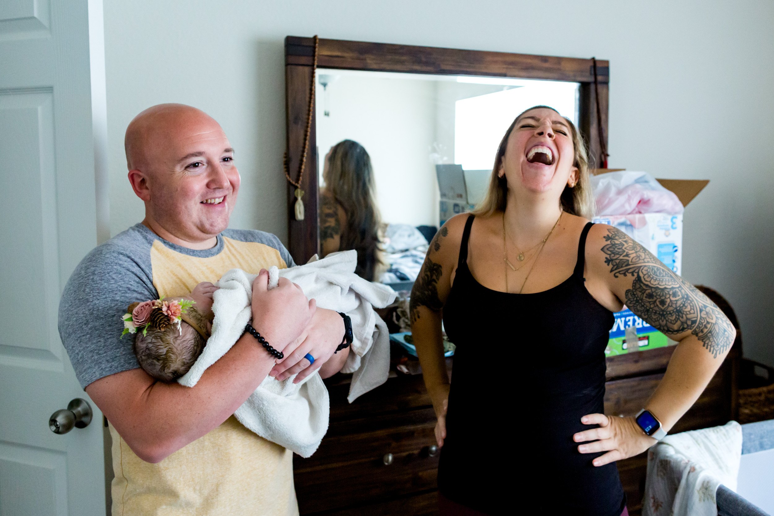 parents laughing together, while holding their newborn baby girl