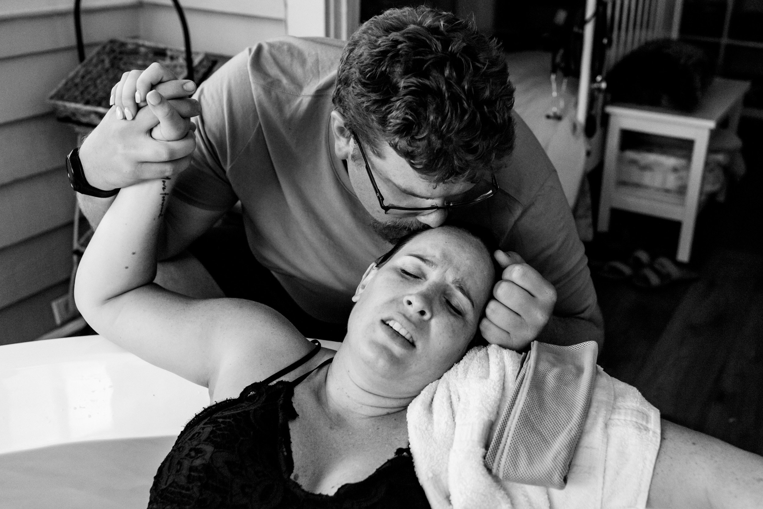 fiance supporting birth mom during labor by giving her a kiss on the head
