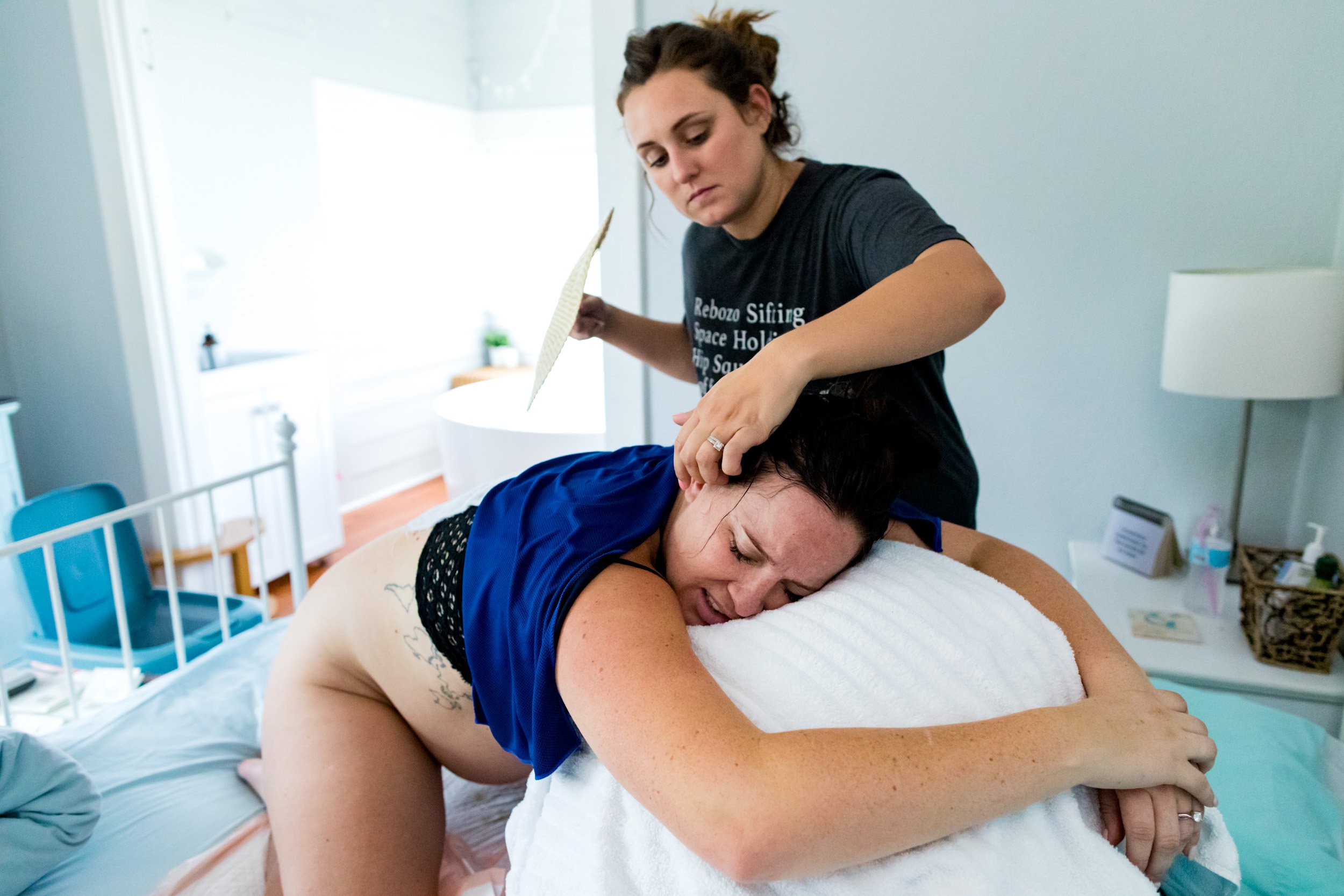 doula gently pulling the hair away from her laboring client's face