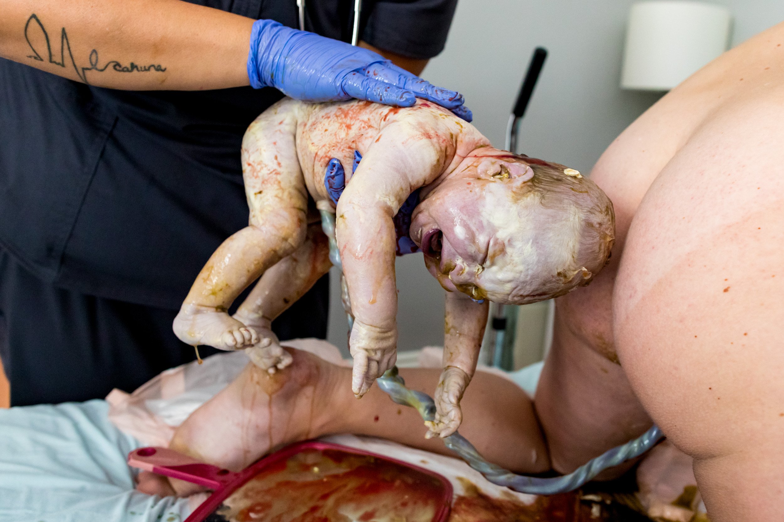 baby being held by midwife seconds after being born