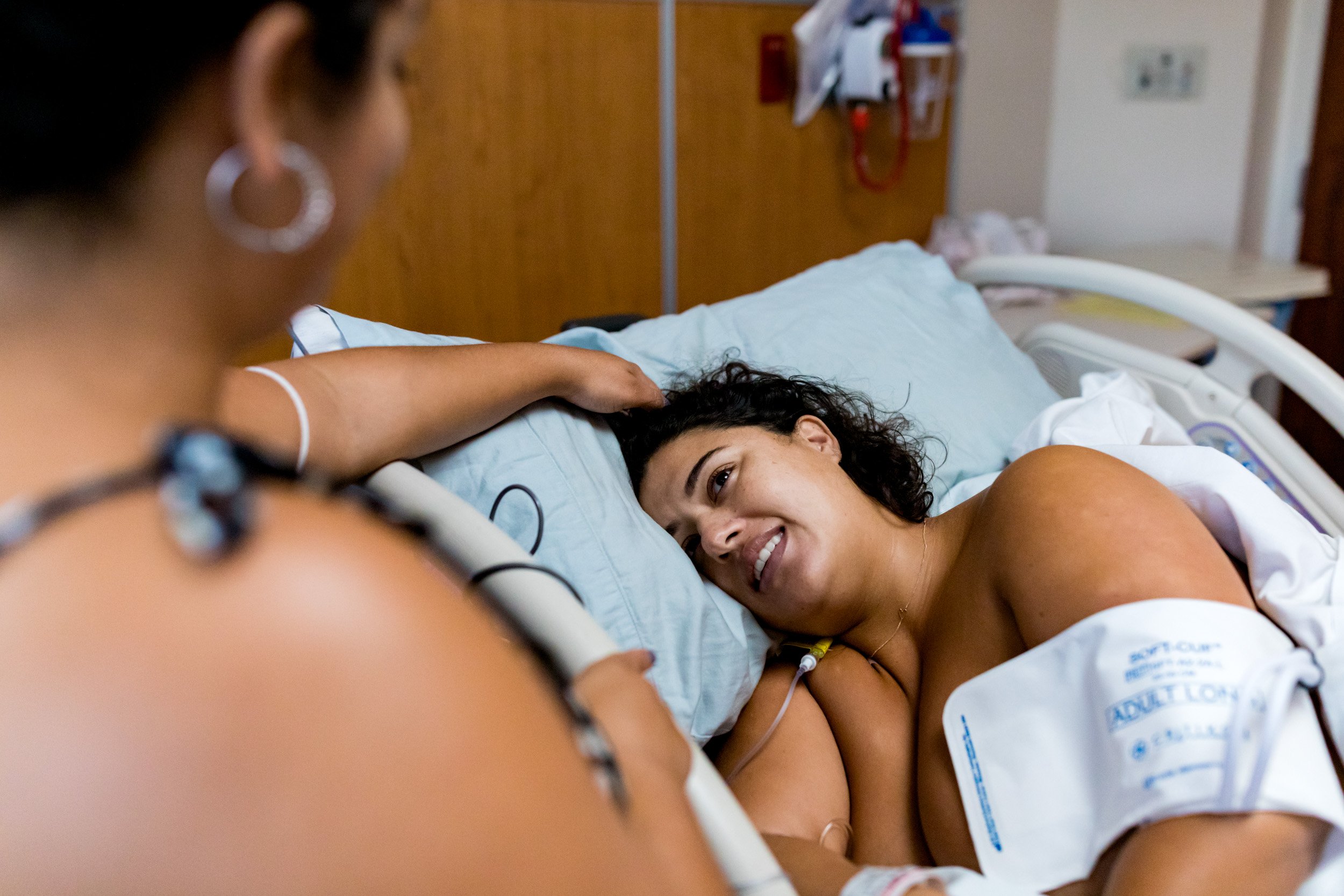 birth mom smiling at her sister while resting in a hospital bed