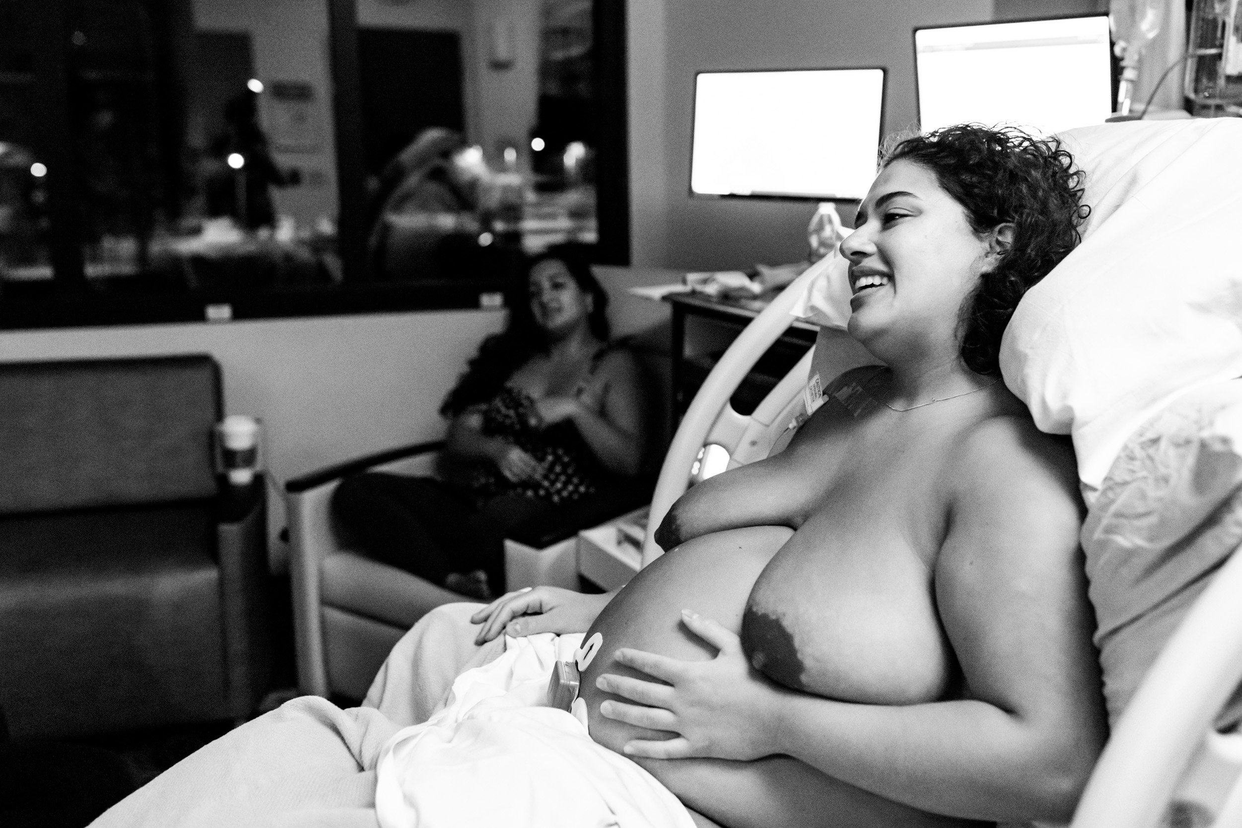 birth mom smiling while holding her pregnant belly