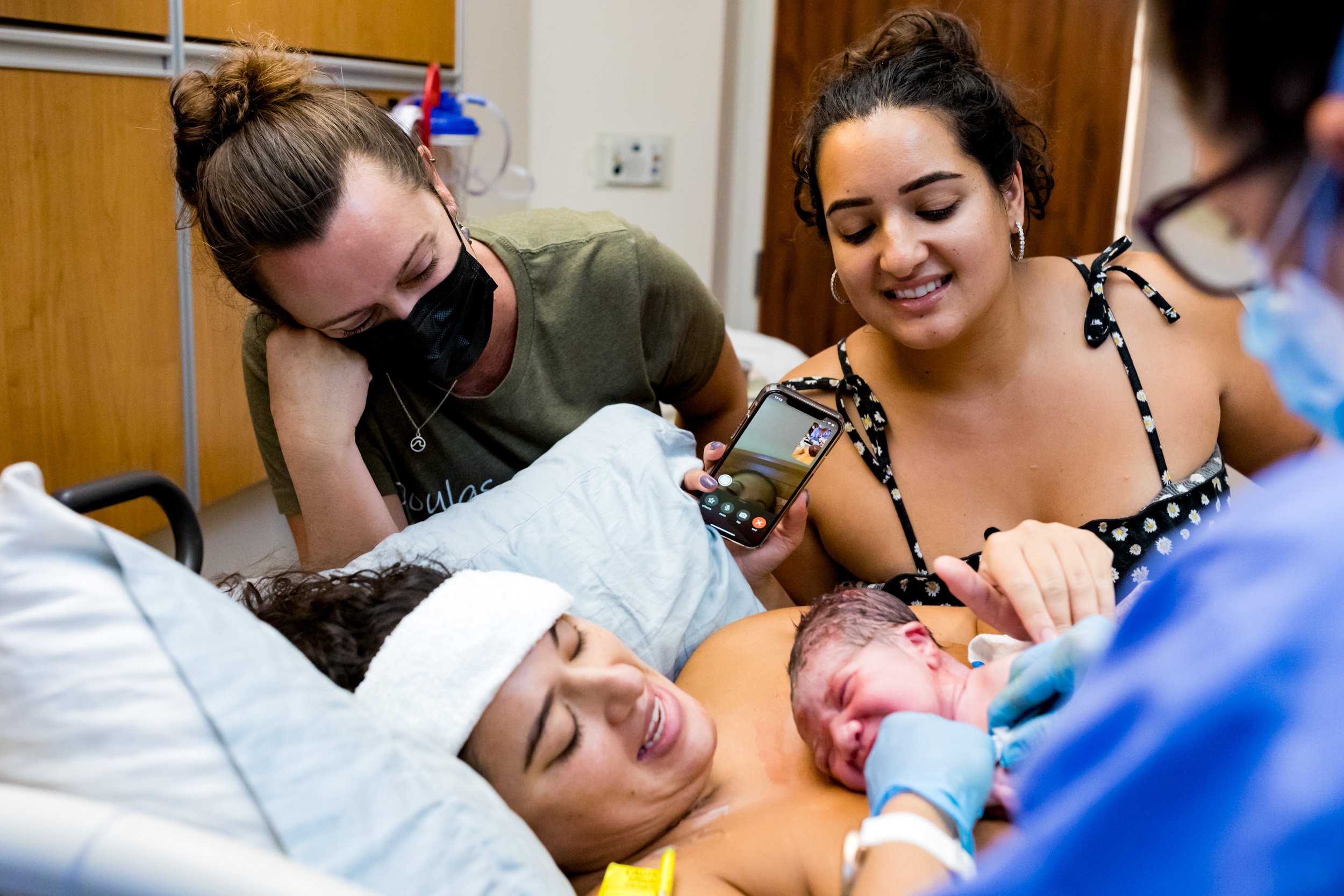doula and aunt admiring newborn baby boy just after birth