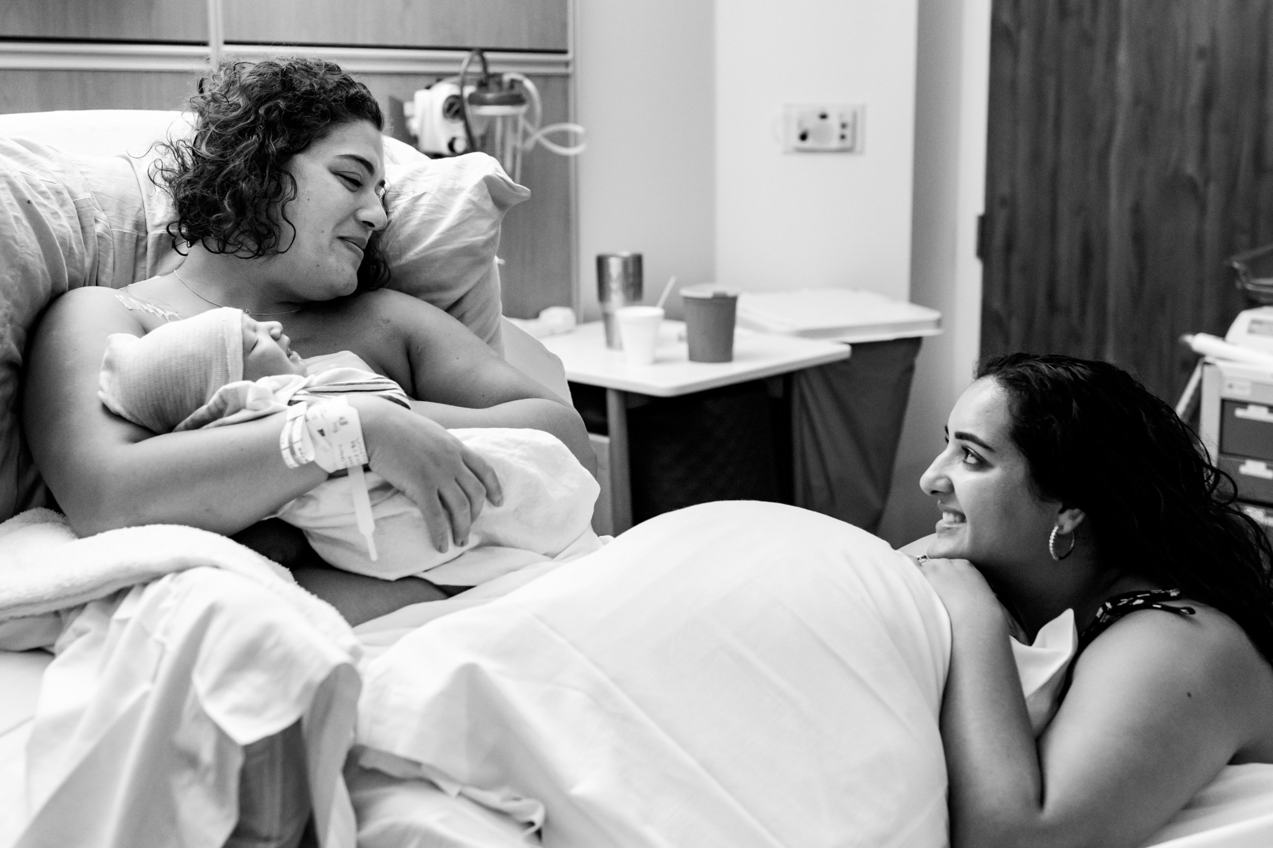 woman holding baby just after birth, while her sister looks on with admiration