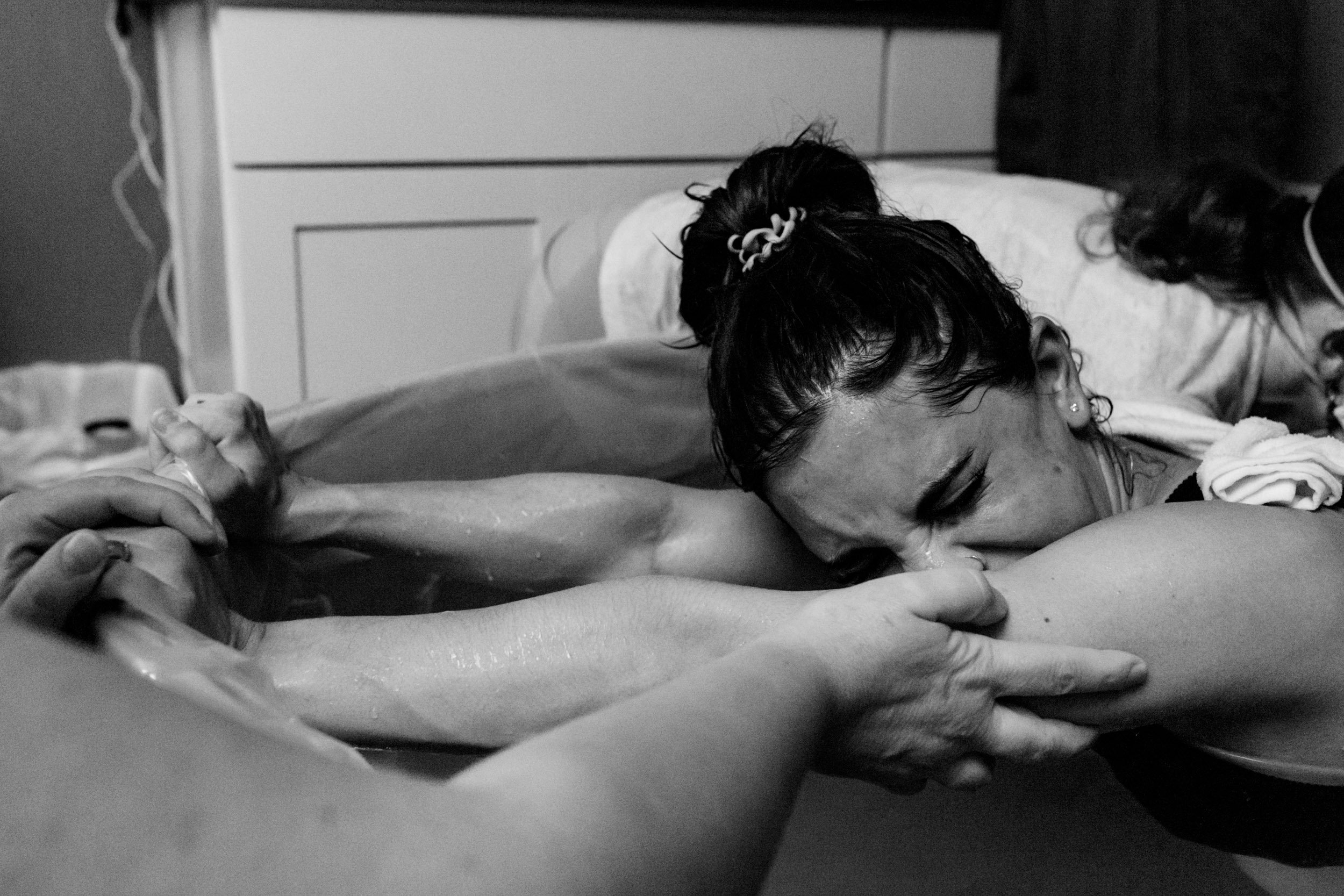 mom in labor holding onto the side of the birth tub