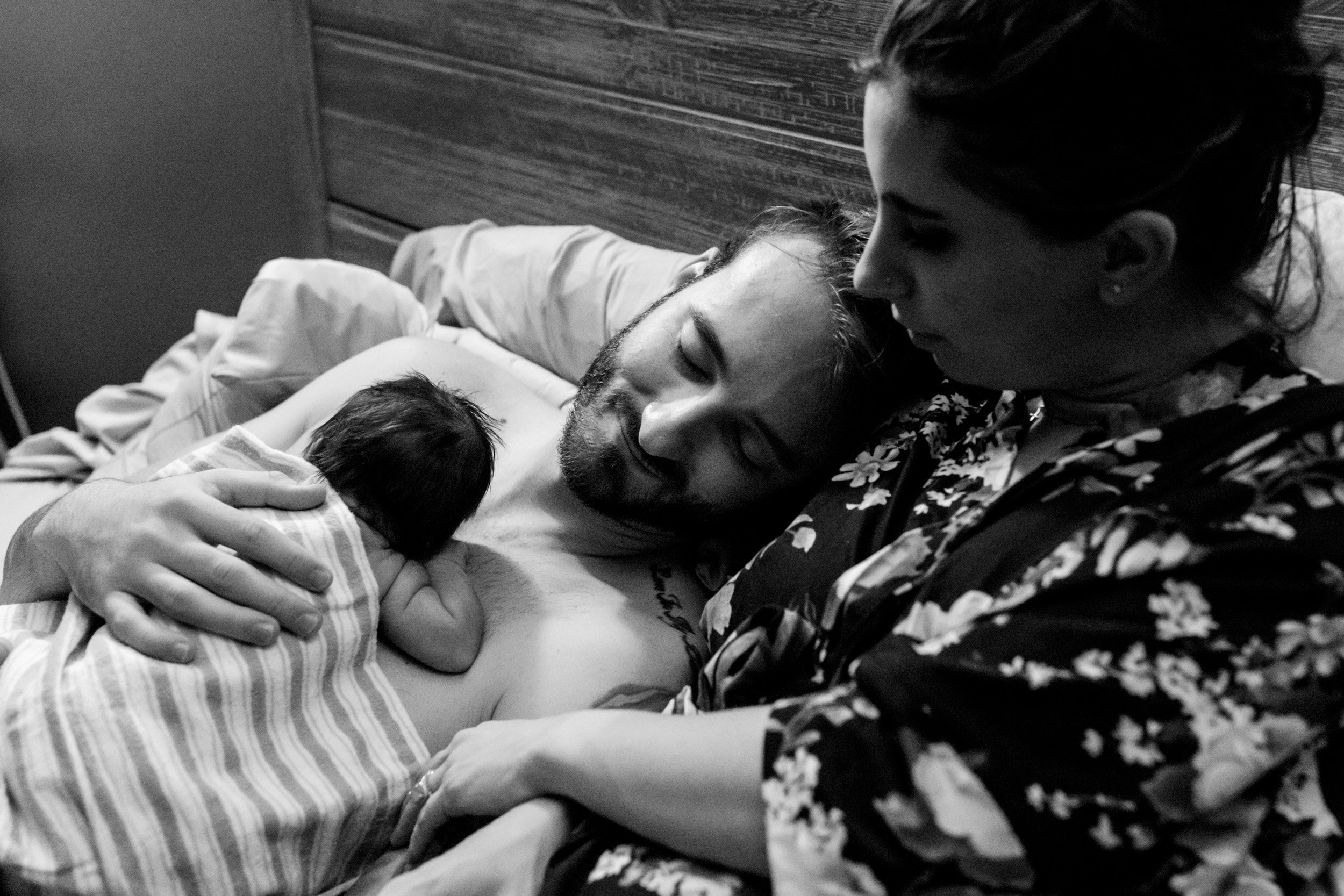 new parents resting with their baby girl just after birth