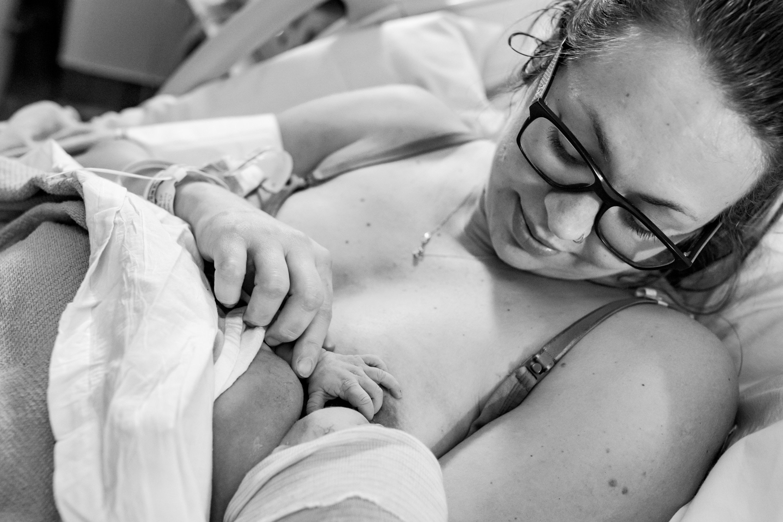 mom smiling at her newborn baby girl as she nurses