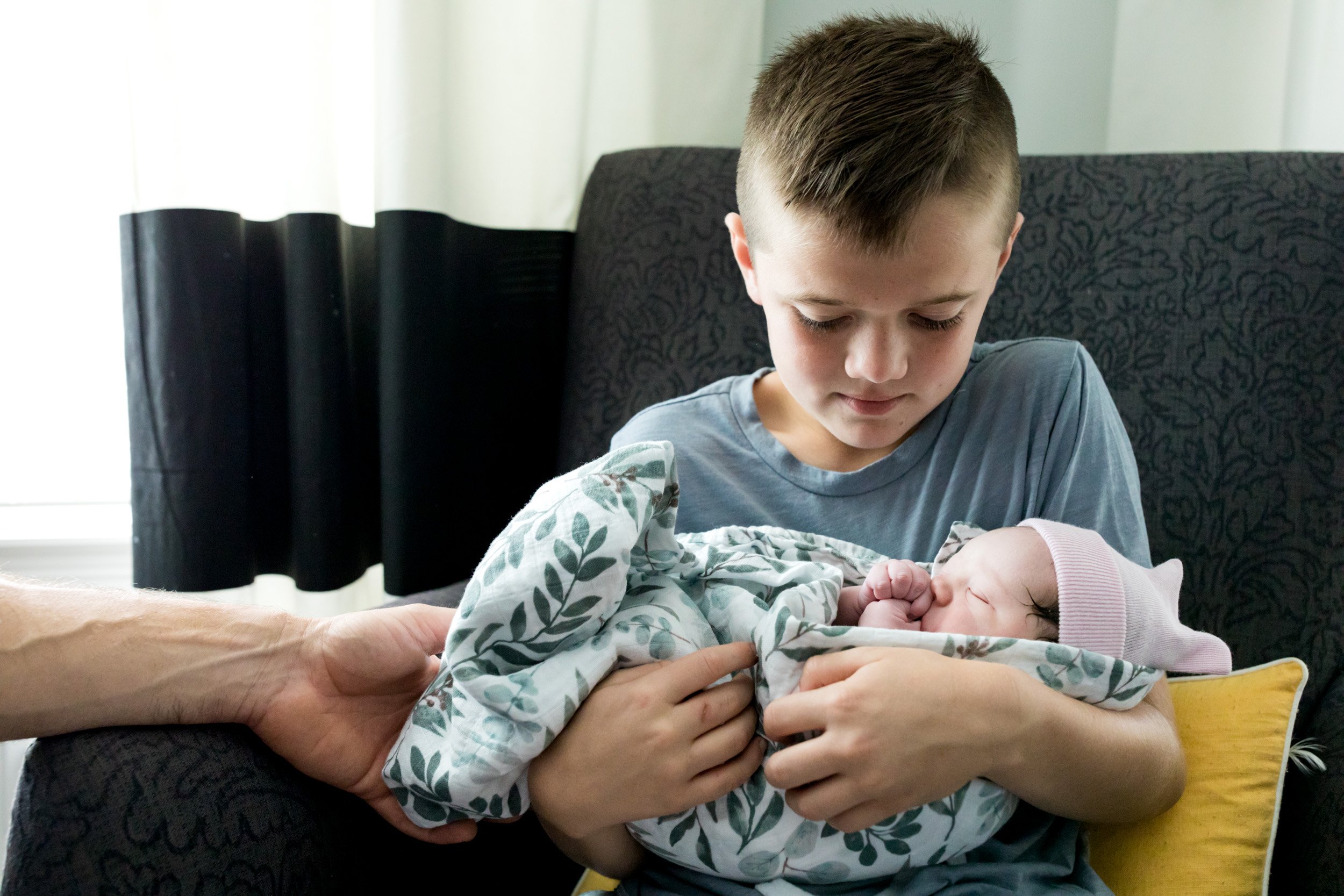 brother holding his newborn baby sister just after birth