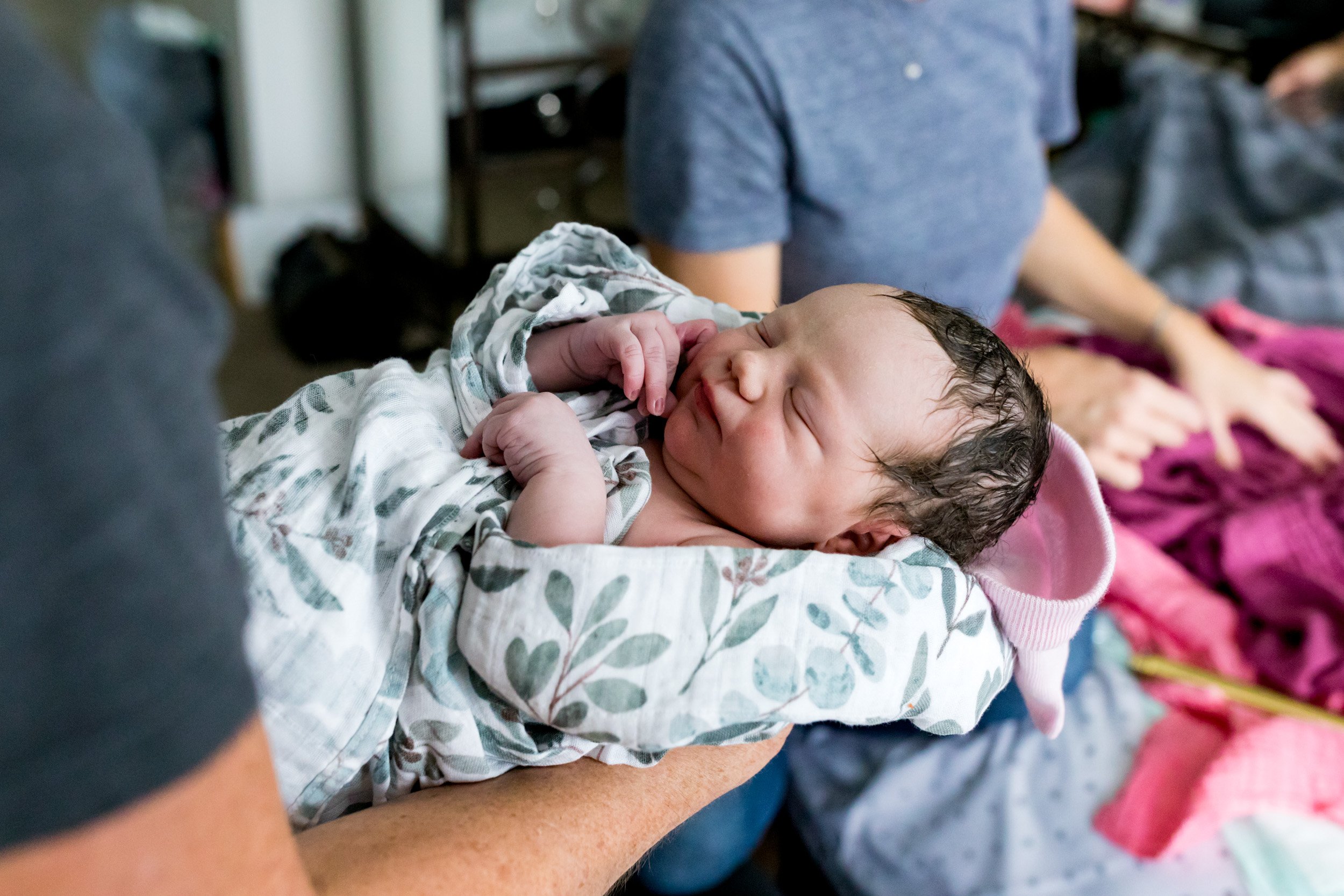 midwife holding newborn baby just before doing the newborn exam