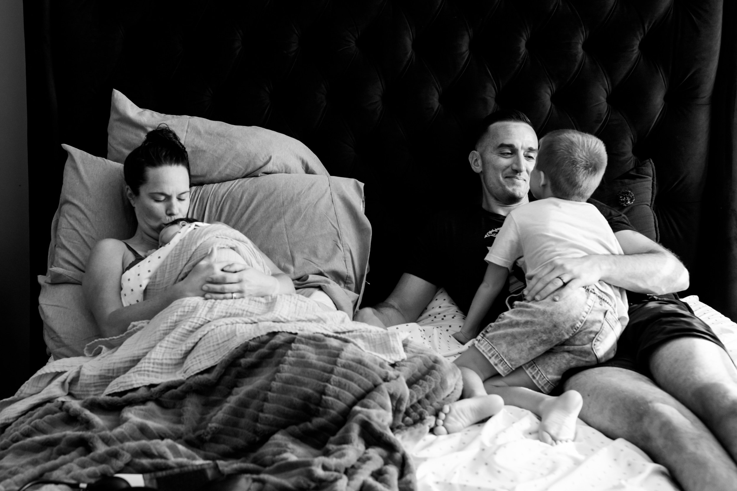 dad smiling at little boy while mom smiles at the newborn baby girl