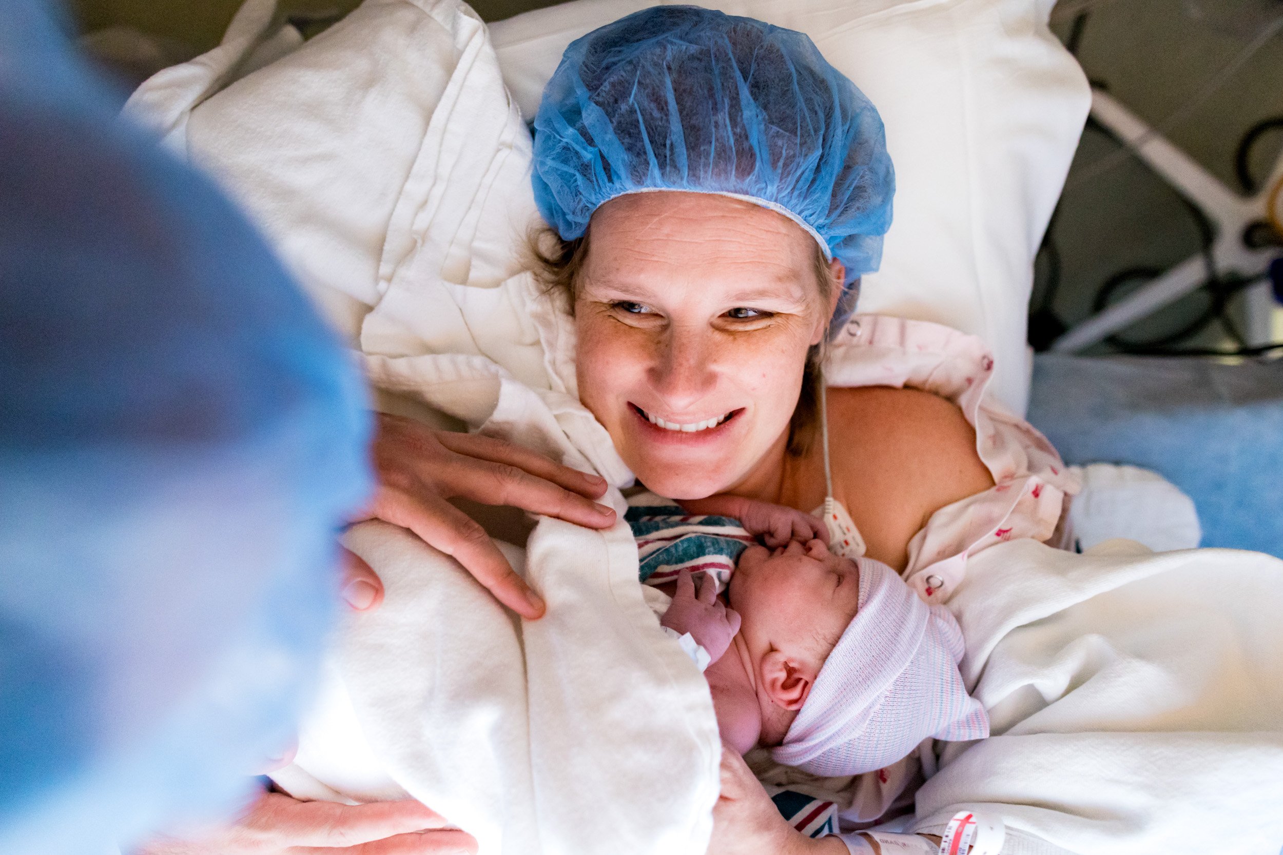 jacksonville birth mom holding her newborn baby just after birth and smiling while looking at her husband