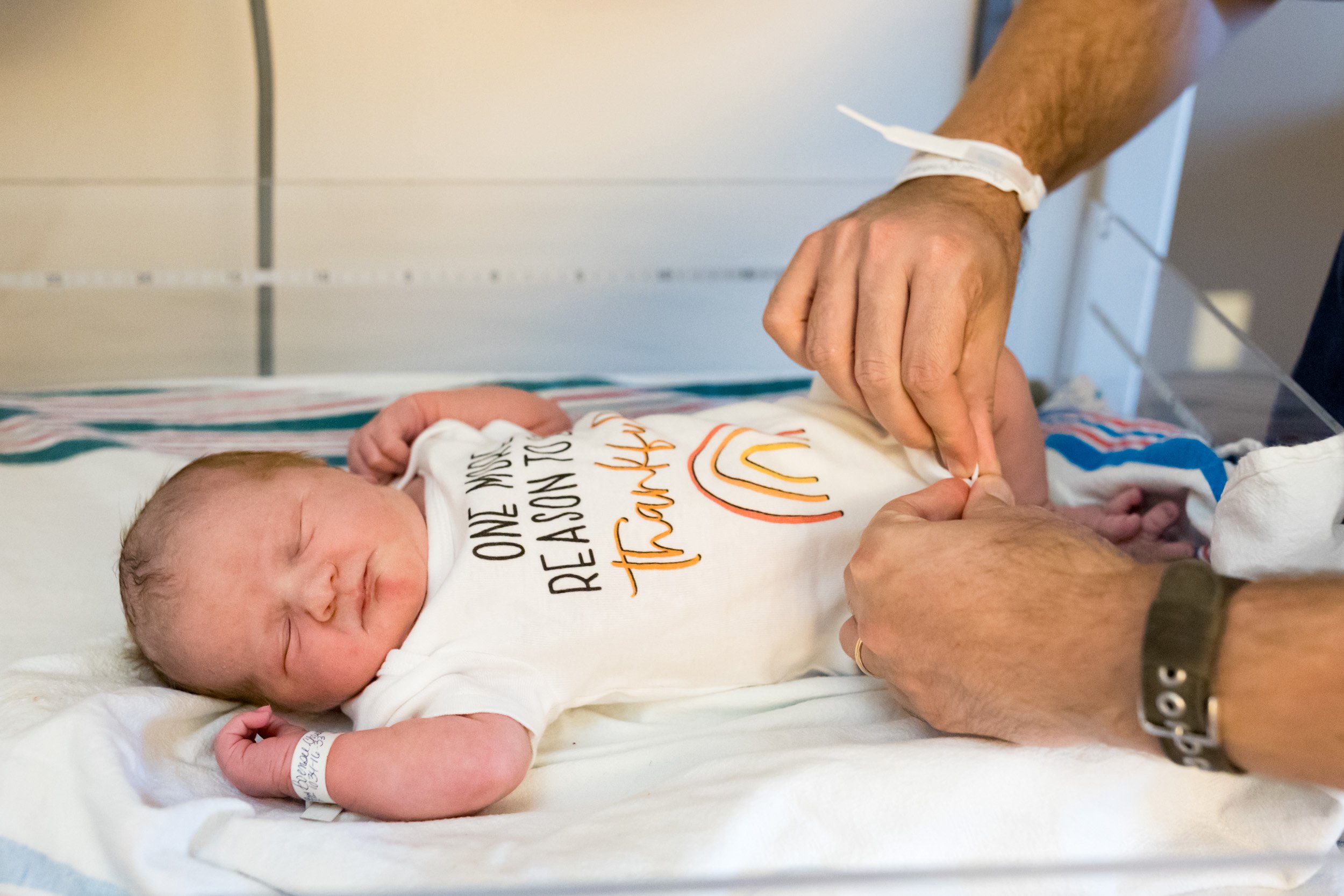 dad putting outfit on newborn baby girl