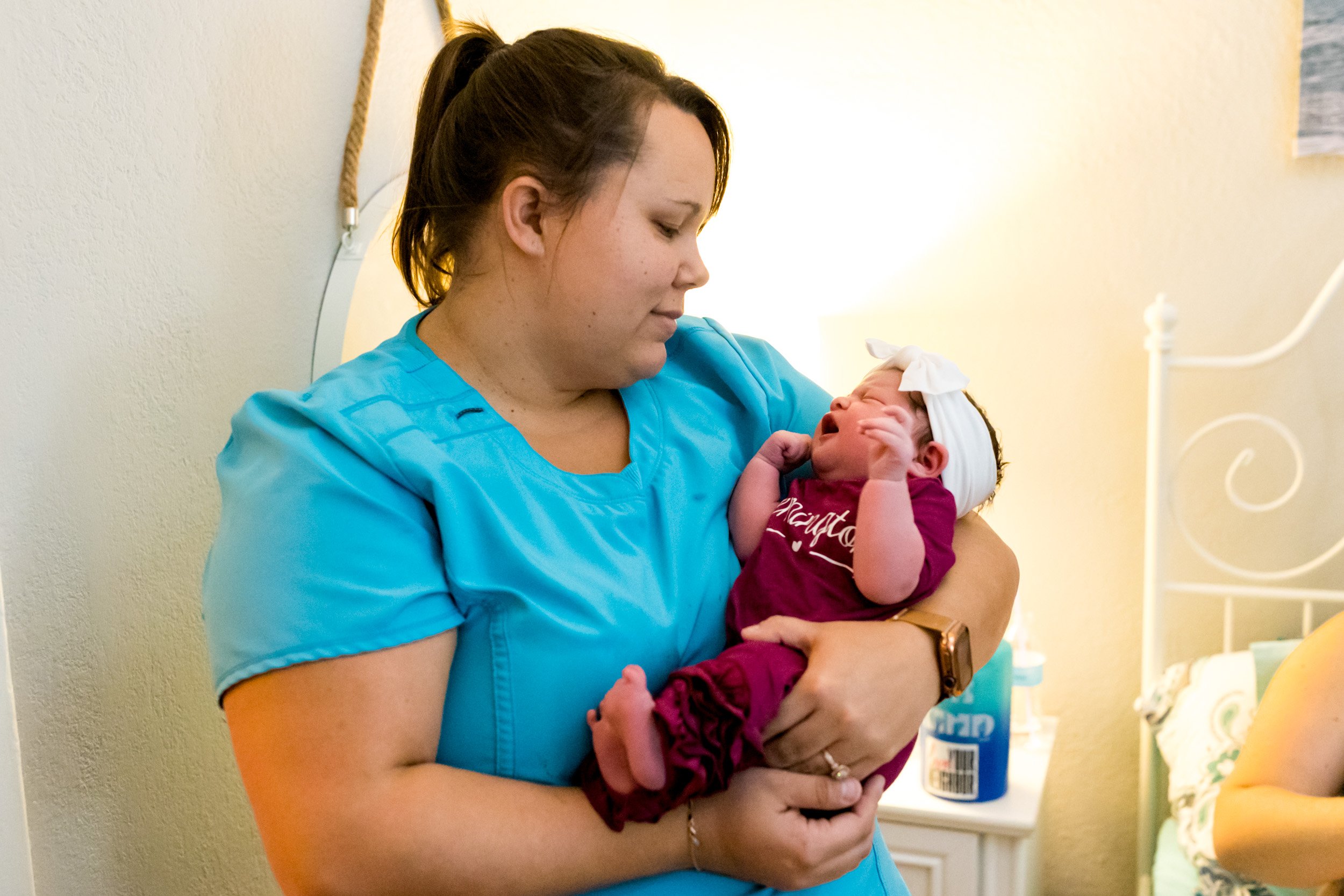 midwife holding baby girl just after birth